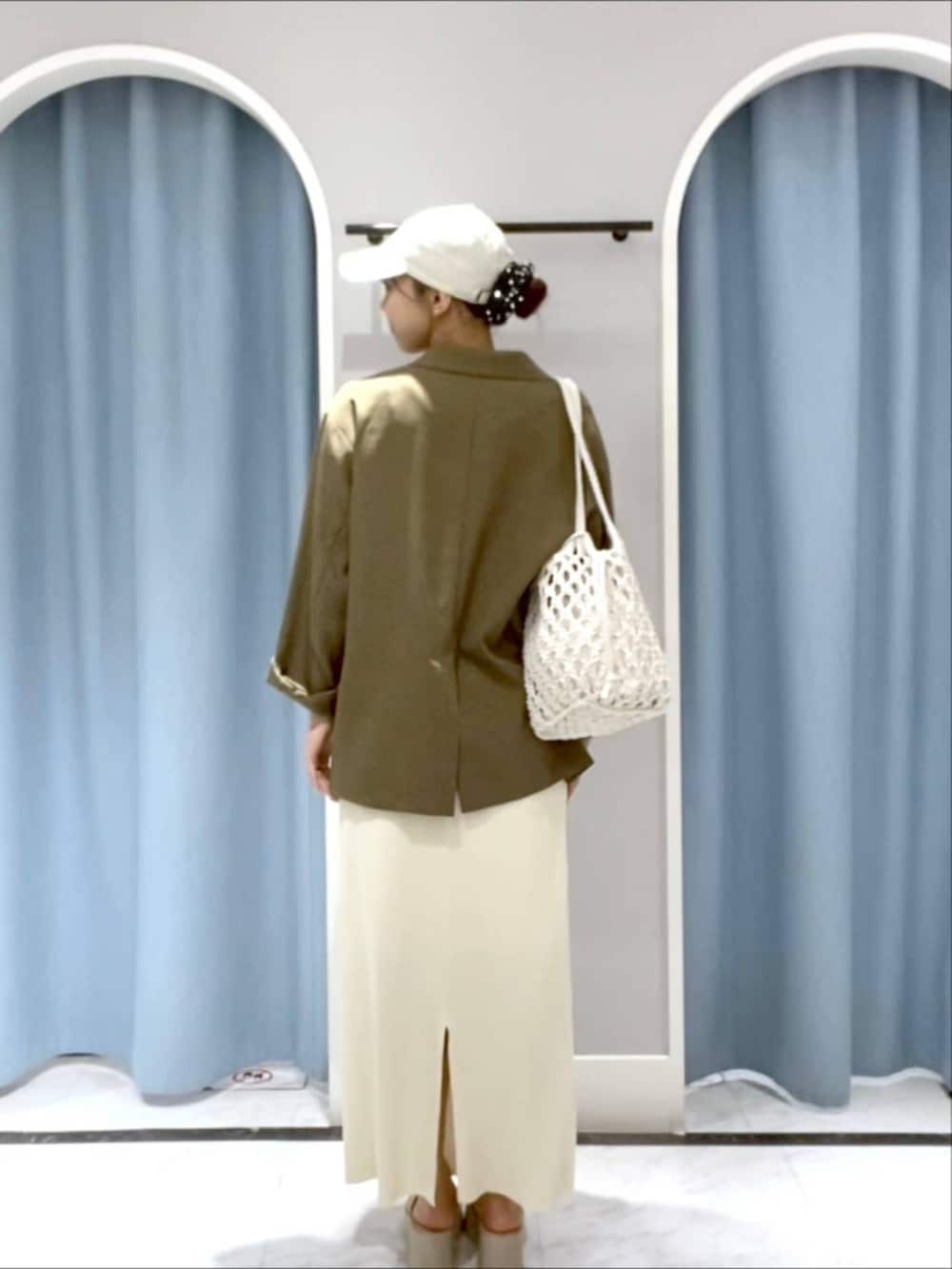 ホワイト系のスカート、グリーン系のテーラードジャケット、ホワイト系のサンダルを着用したレディースの春コーディネートの3枚目の写真