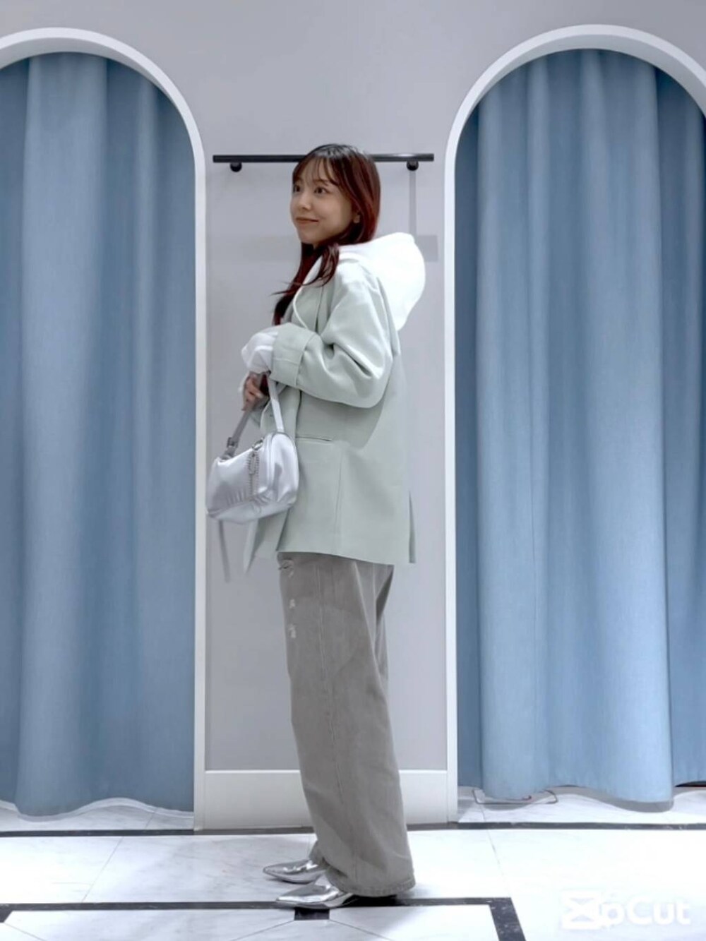 グリーン系のテーラードジャケット、シルバー系のトートバッグ、グレー系のデニムパンツを着用したレディースの春コーディネートの2枚目の写真