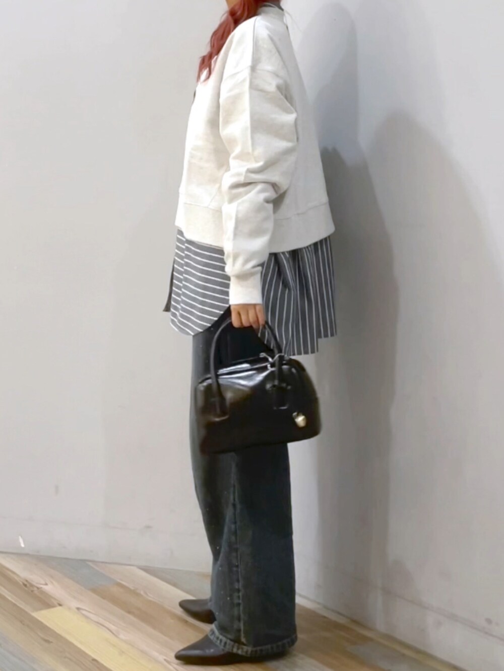 ブラック系のブーツ、ブルー系のデニムパンツを着用したレディースの秋コーディネートの2枚目の写真