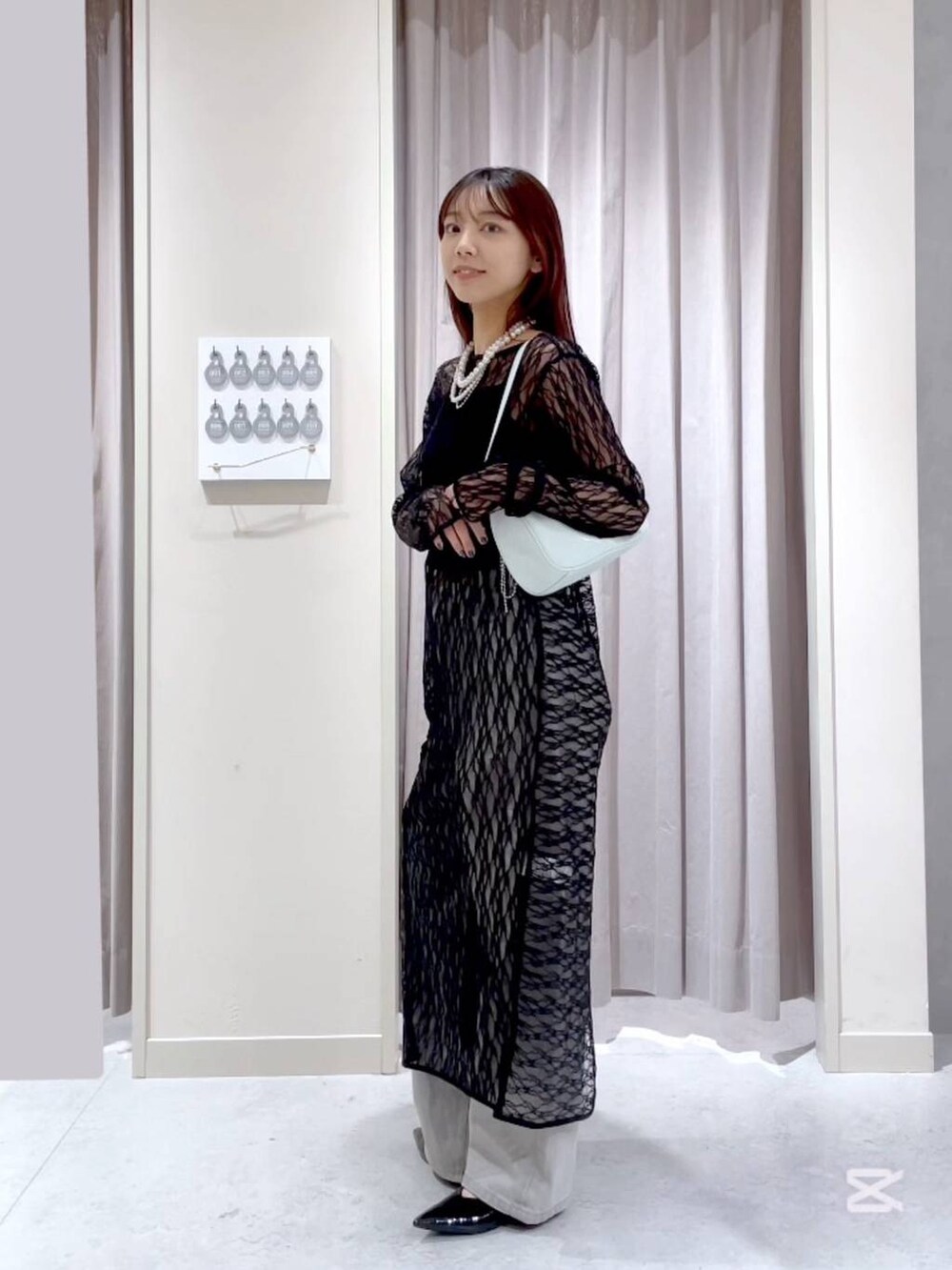 グレー系のデニムパンツ、グリーン系のトートバッグ、ブラック系のワンピースを着用したレディースの春コーディネートの3枚目の写真