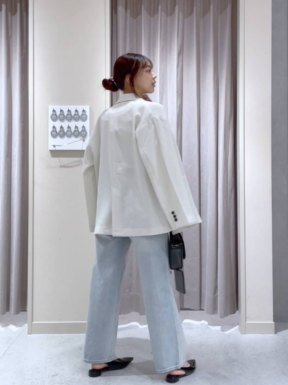 ホワイト系のテーラードジャケット、ブルー系のデニムパンツ、ブラック系のショルダーバッグを着用したレディースの春コーディネートの3枚目の写真