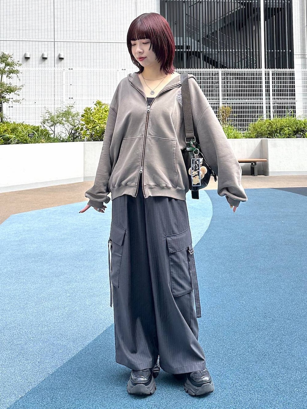 ブラック系のスニーカー、グレー系のスラックス、ブラウン系のパーカーを着用したレディースの秋コーディネートの4枚目の写真