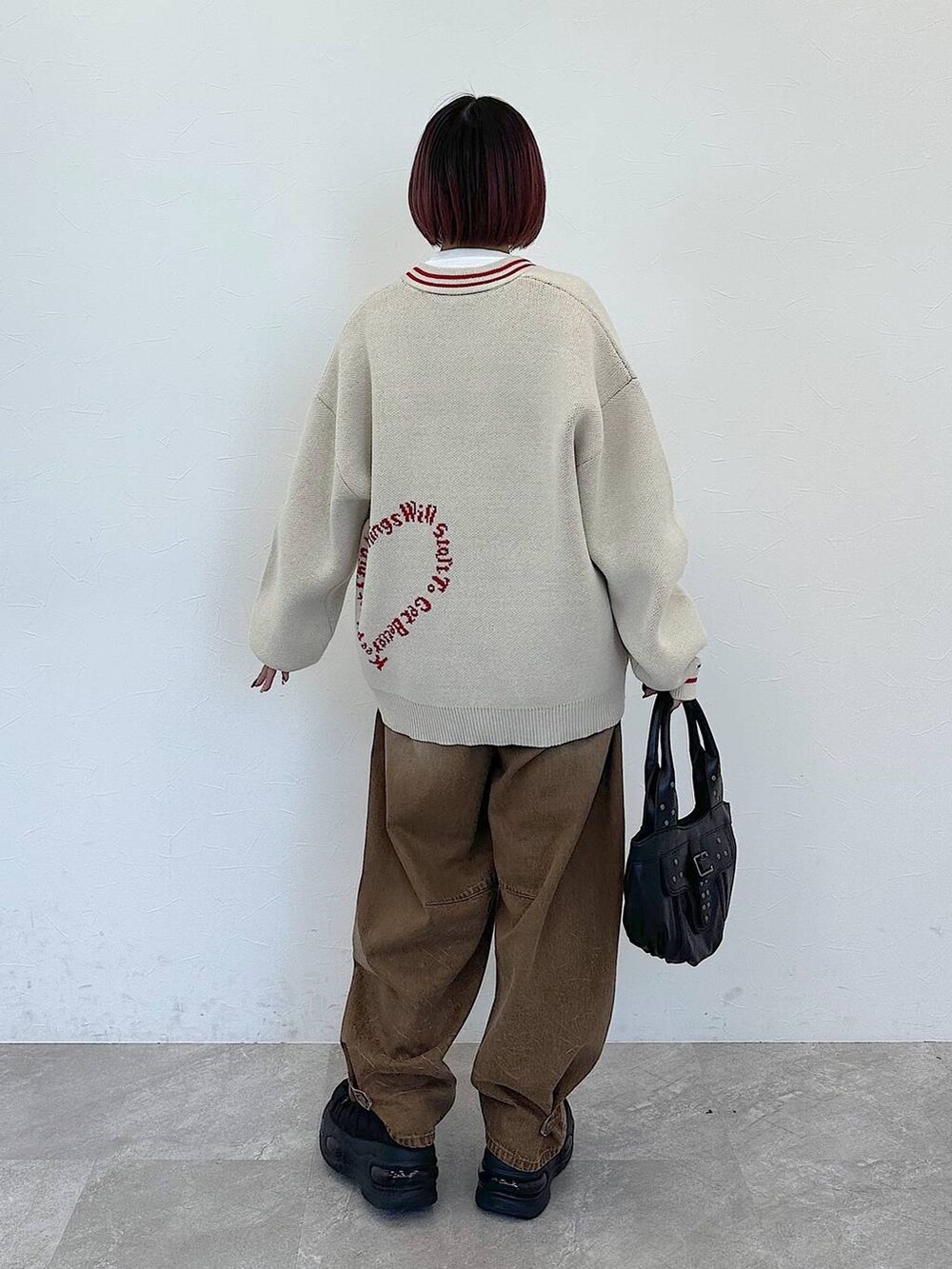 ブラック系のハンドバッグ、ベージュ系のデニムパンツ、ベージュ系のカーディガン/ボレロを着用したレディースの冬コーディネートの6枚目の写真