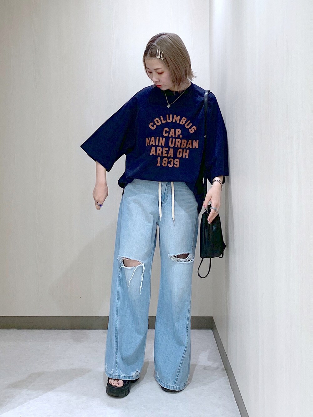 ブルー系のスウェット、ブルー系のデニムパンツ、ブラック系のサンダルを着用したレディースの春コーディネートの3枚目の写真