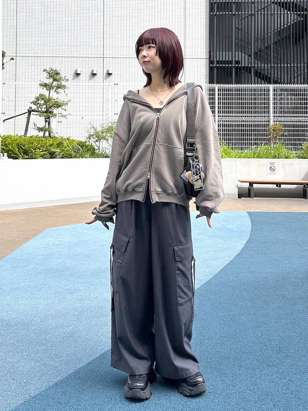 ブラック系のスニーカー、グレー系のスラックス、ブラウン系のパーカーを着用したレディースの秋コーディネートの2枚目の写真