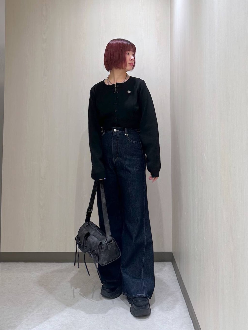 ブラック系のショルダーバッグ、ブルー系のデニムパンツ、ブラック系のスニーカーを着用したレディースの秋コーディネートの2枚目の写真