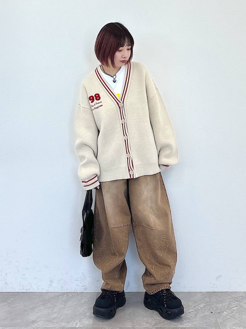 ブラック系のハンドバッグ、ベージュ系のデニムパンツ、ベージュ系のカーディガン/ボレロを着用したレディースの冬コーディネートの3枚目の写真