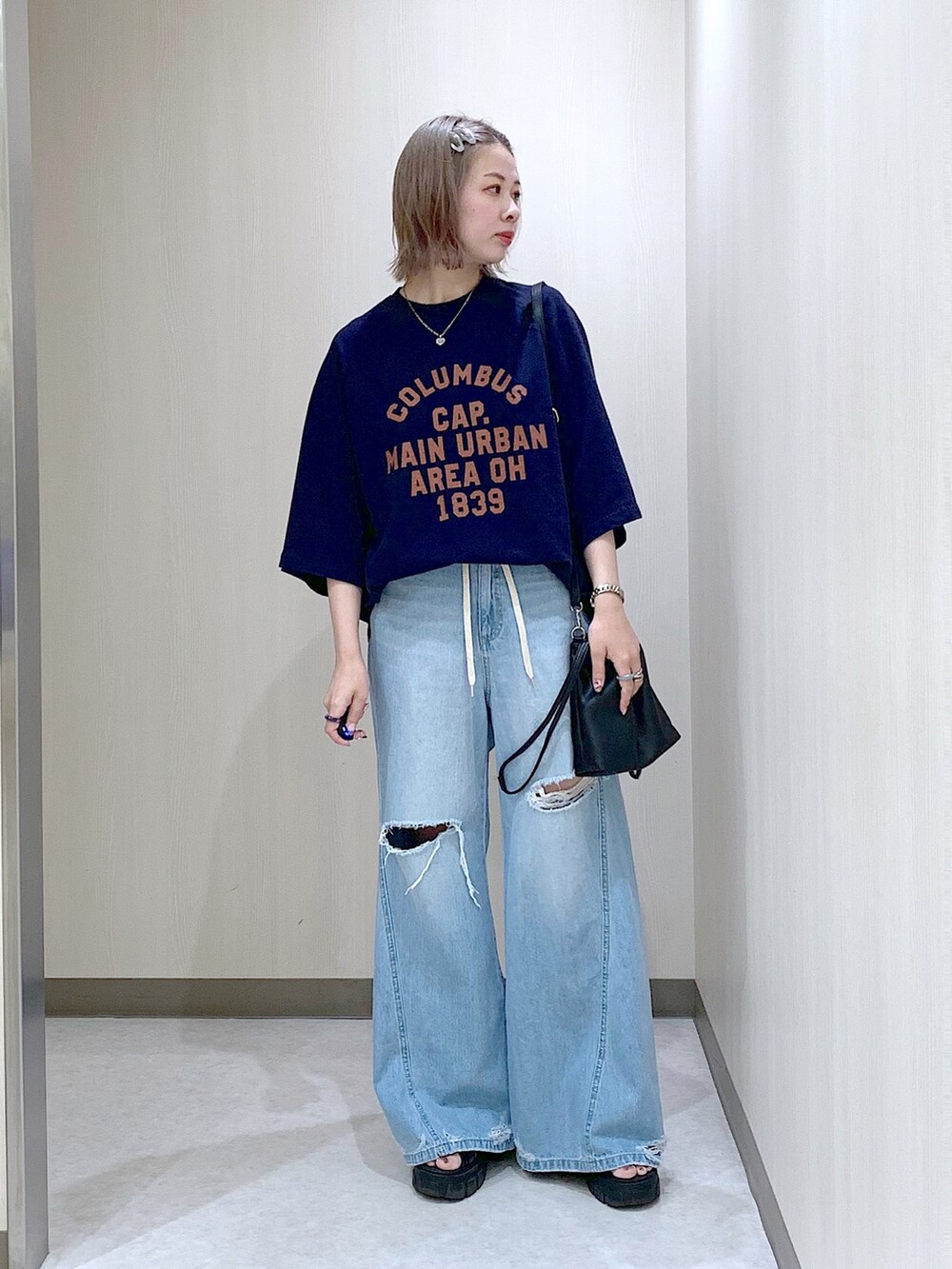 ブルー系のスウェット、ブルー系のデニムパンツ、ブラック系のサンダルを着用したレディースの春コーディネートの2枚目の写真
