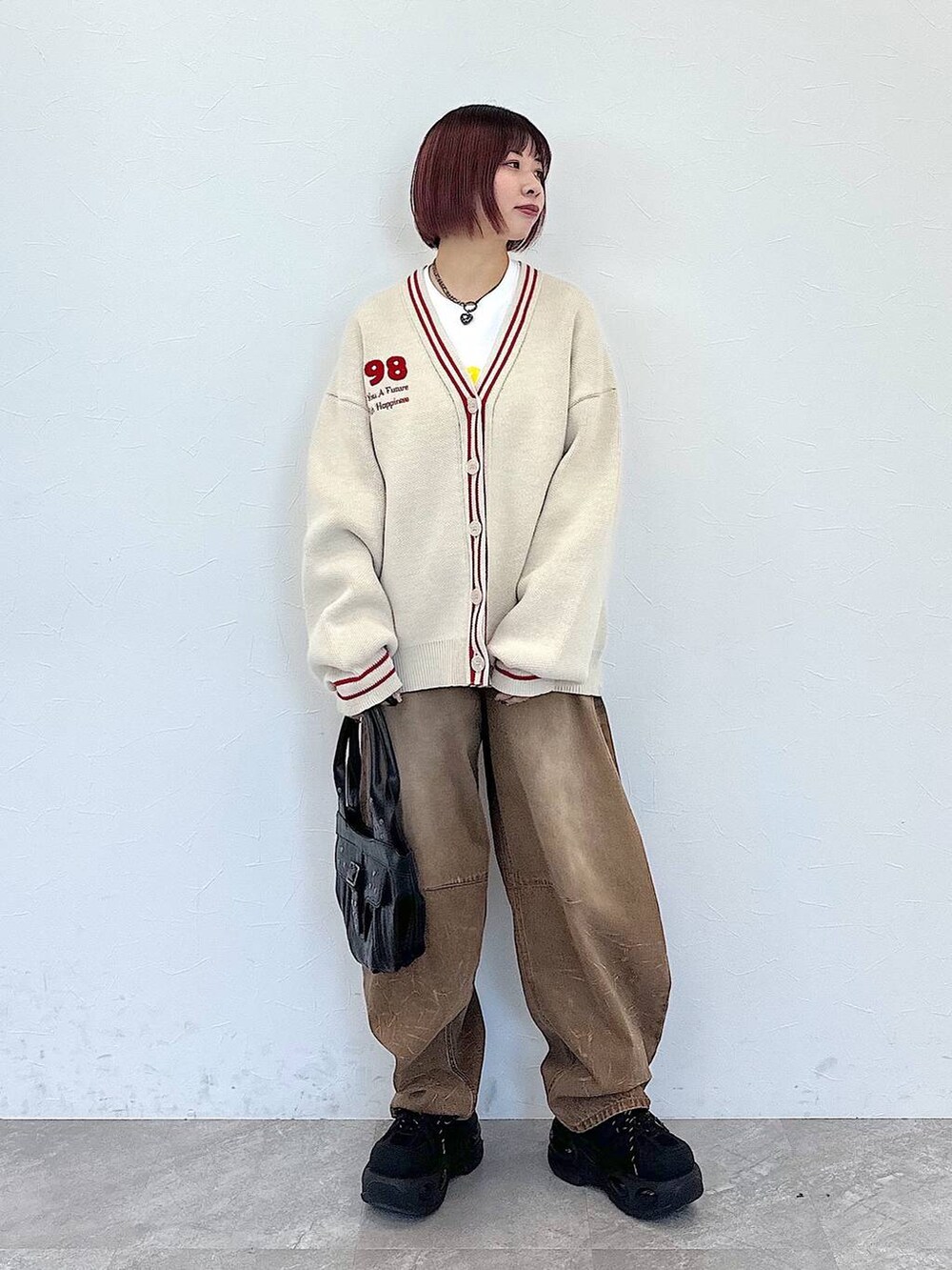 ブラック系のハンドバッグ、ベージュ系のデニムパンツ、ベージュ系のカーディガン/ボレロを着用したレディースの冬コーディネートの2枚目の写真