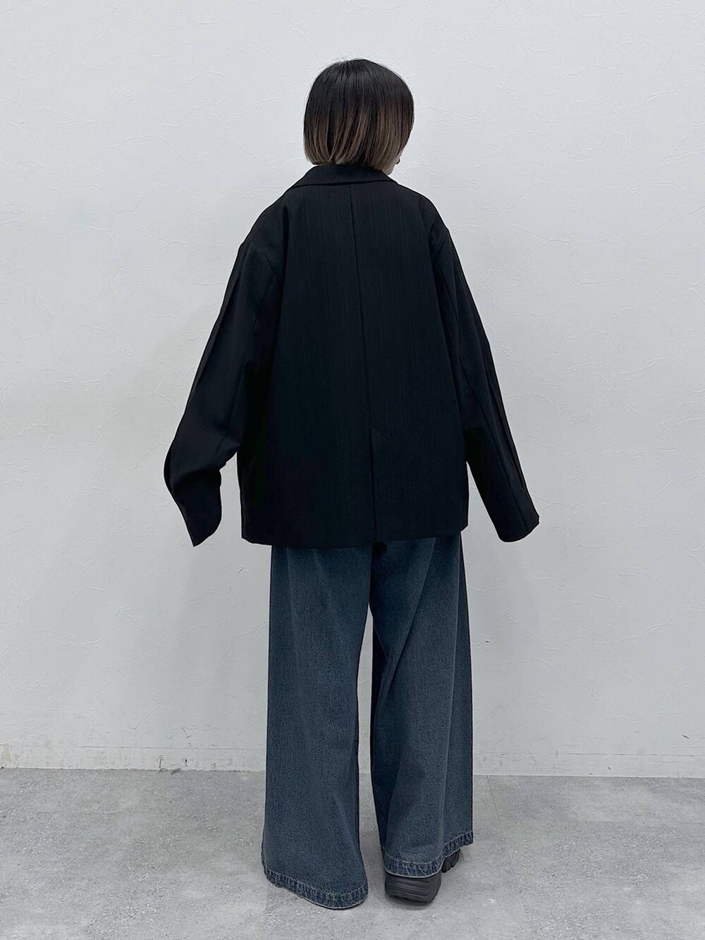 ブルー系のデニムパンツ、ブラック系のテーラードジャケット、ベージュ系のTシャツ/カットソーを着用したレディースの春コーディネートの5枚目の写真
