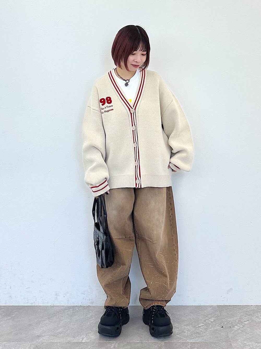 ブラック系のハンドバッグ、ベージュ系のデニムパンツ、ベージュ系のカーディガン/ボレロを着用したレディースの冬コーディネートの4枚目の写真