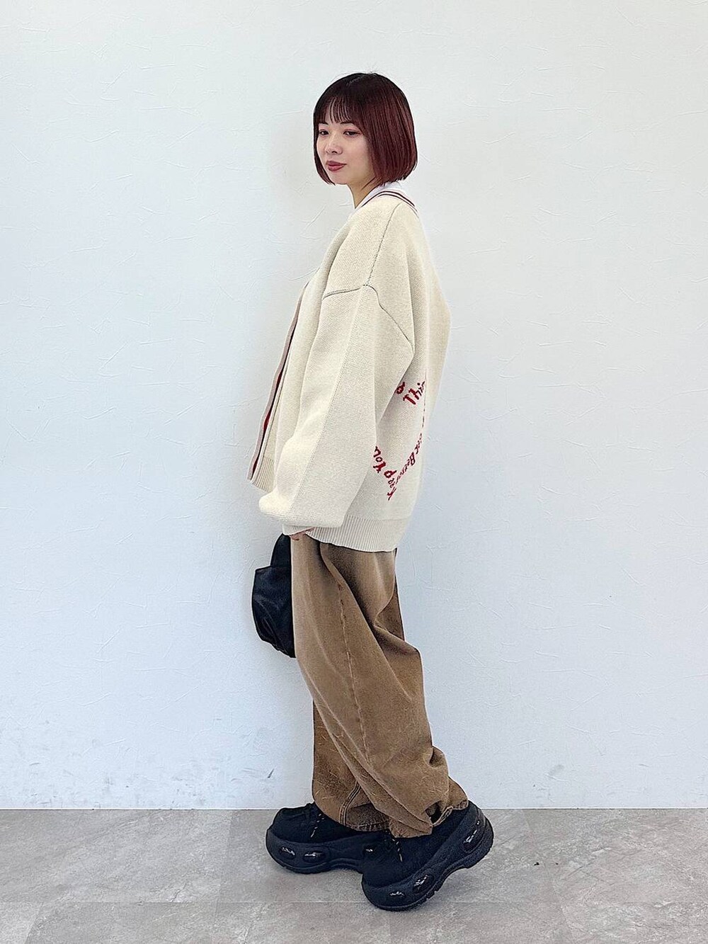 ブラック系のハンドバッグ、ベージュ系のデニムパンツ、ベージュ系のカーディガン/ボレロを着用したレディースの冬コーディネートの5枚目の写真