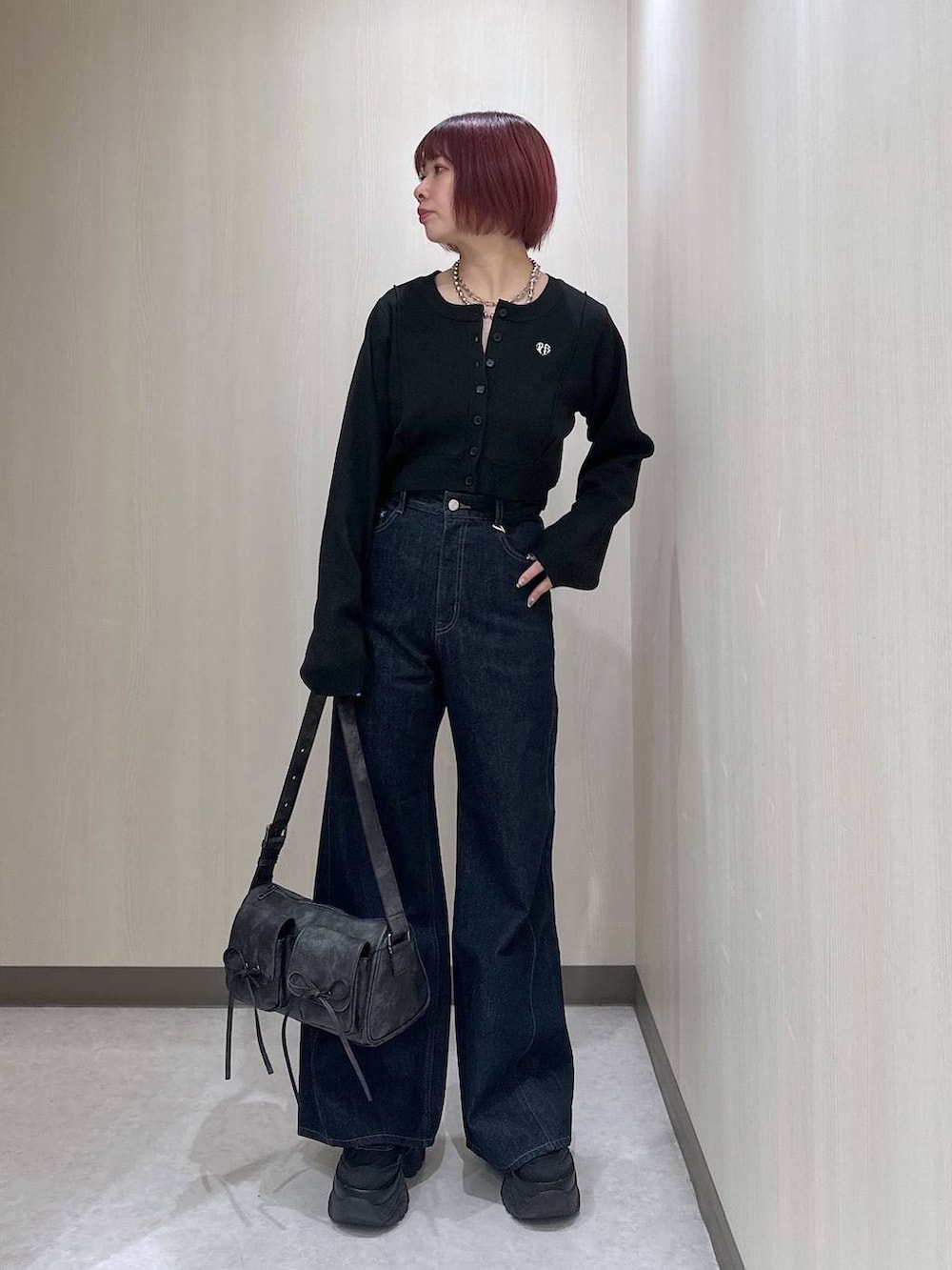 ブラック系のショルダーバッグ、ブルー系のデニムパンツ、ブラック系のスニーカーを着用したレディースの秋コーディネートの4枚目の写真