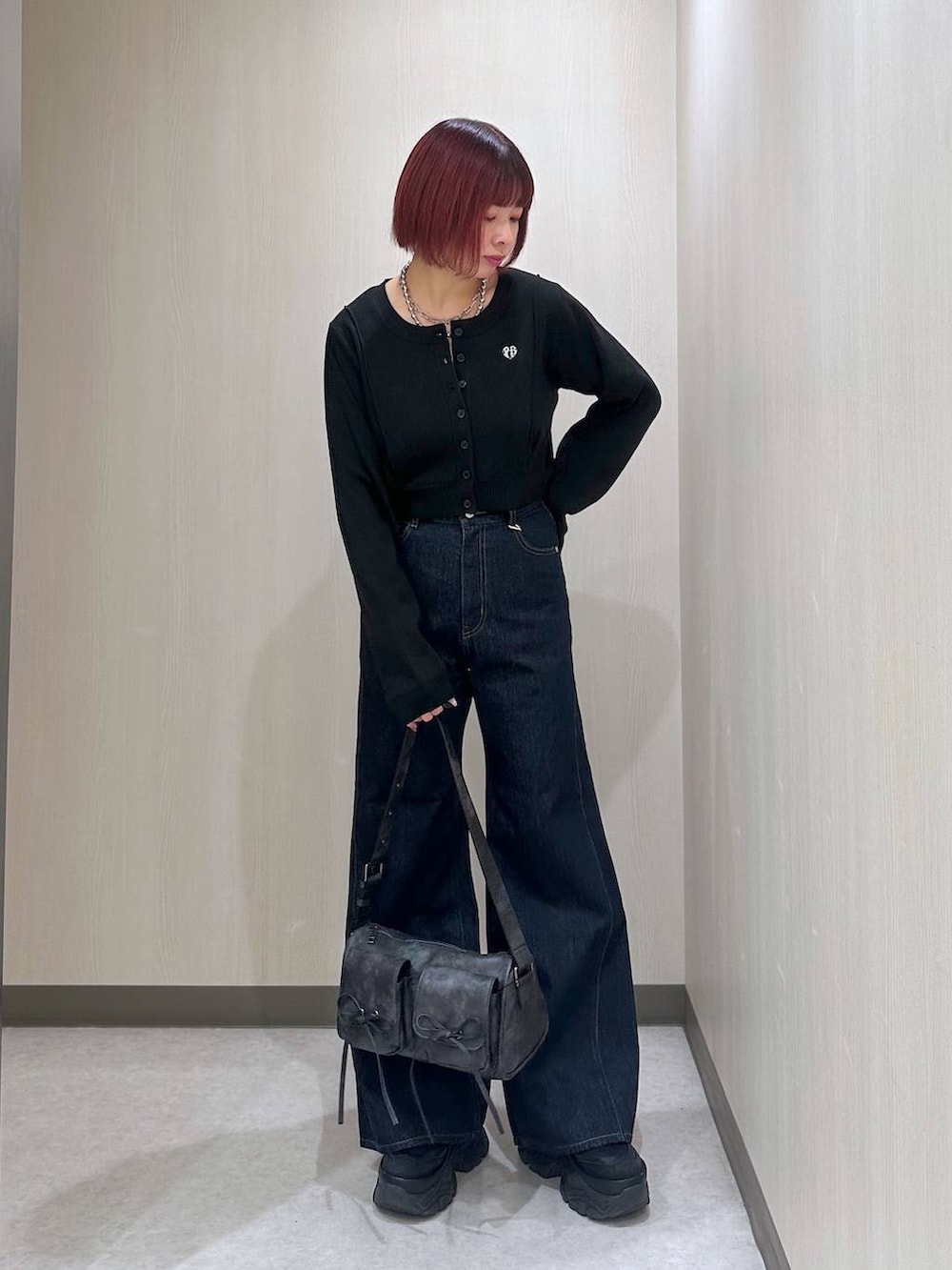 ブラック系のショルダーバッグ、ブルー系のデニムパンツ、ブラック系のスニーカーを着用したレディースの秋コーディネートの3枚目の写真