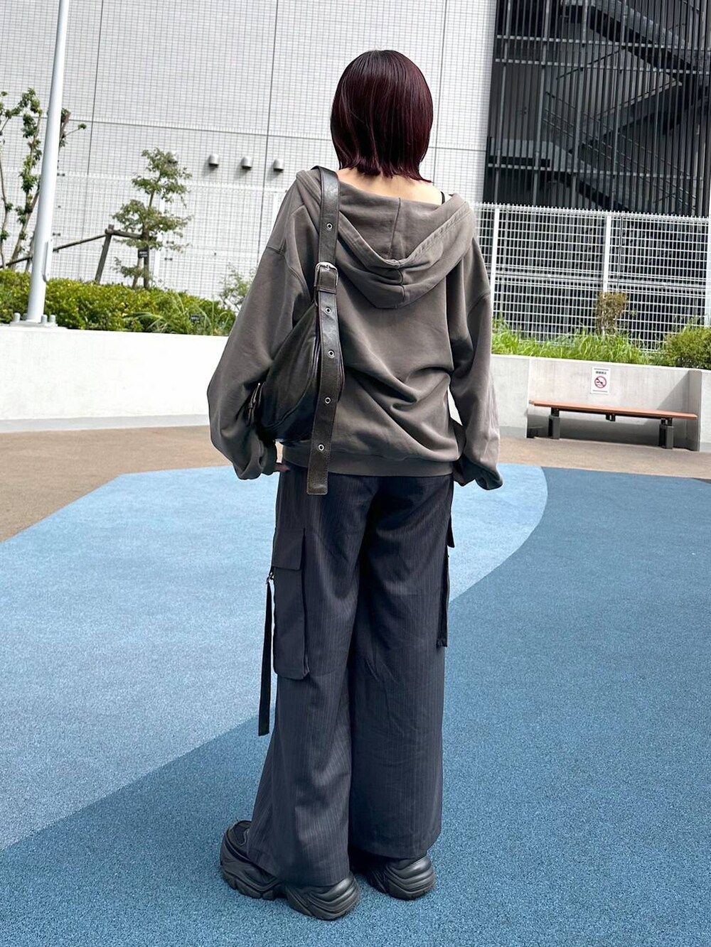 ブラック系のスニーカー、グレー系のスラックス、ブラウン系のパーカーを着用したレディースの秋コーディネートの5枚目の写真