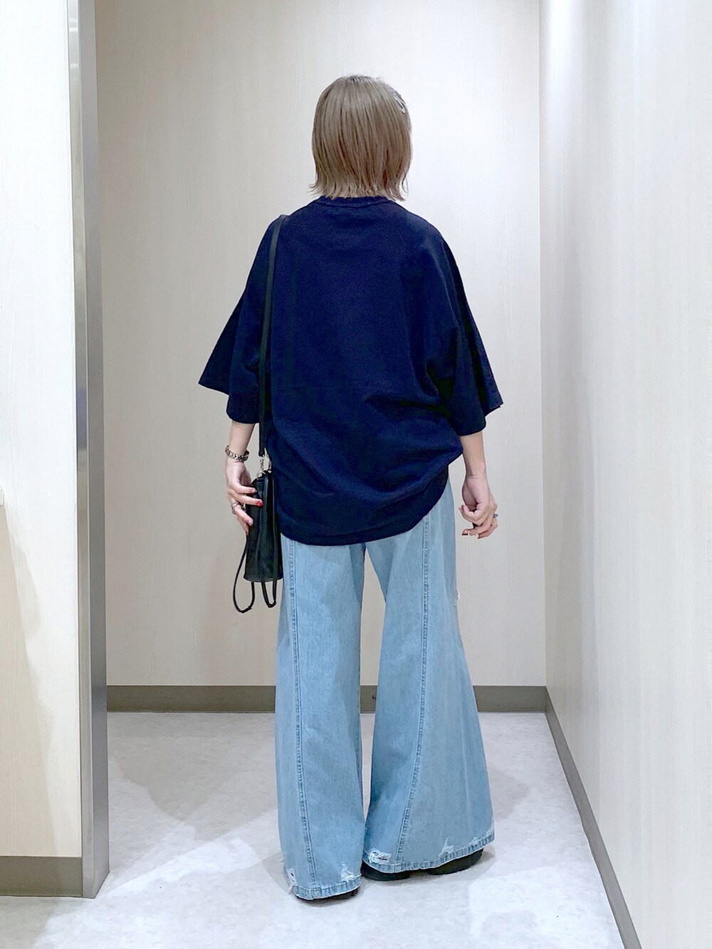 ブルー系のスウェット、ブルー系のデニムパンツ、ブラック系のサンダルを着用したレディースの春コーディネートの5枚目の写真