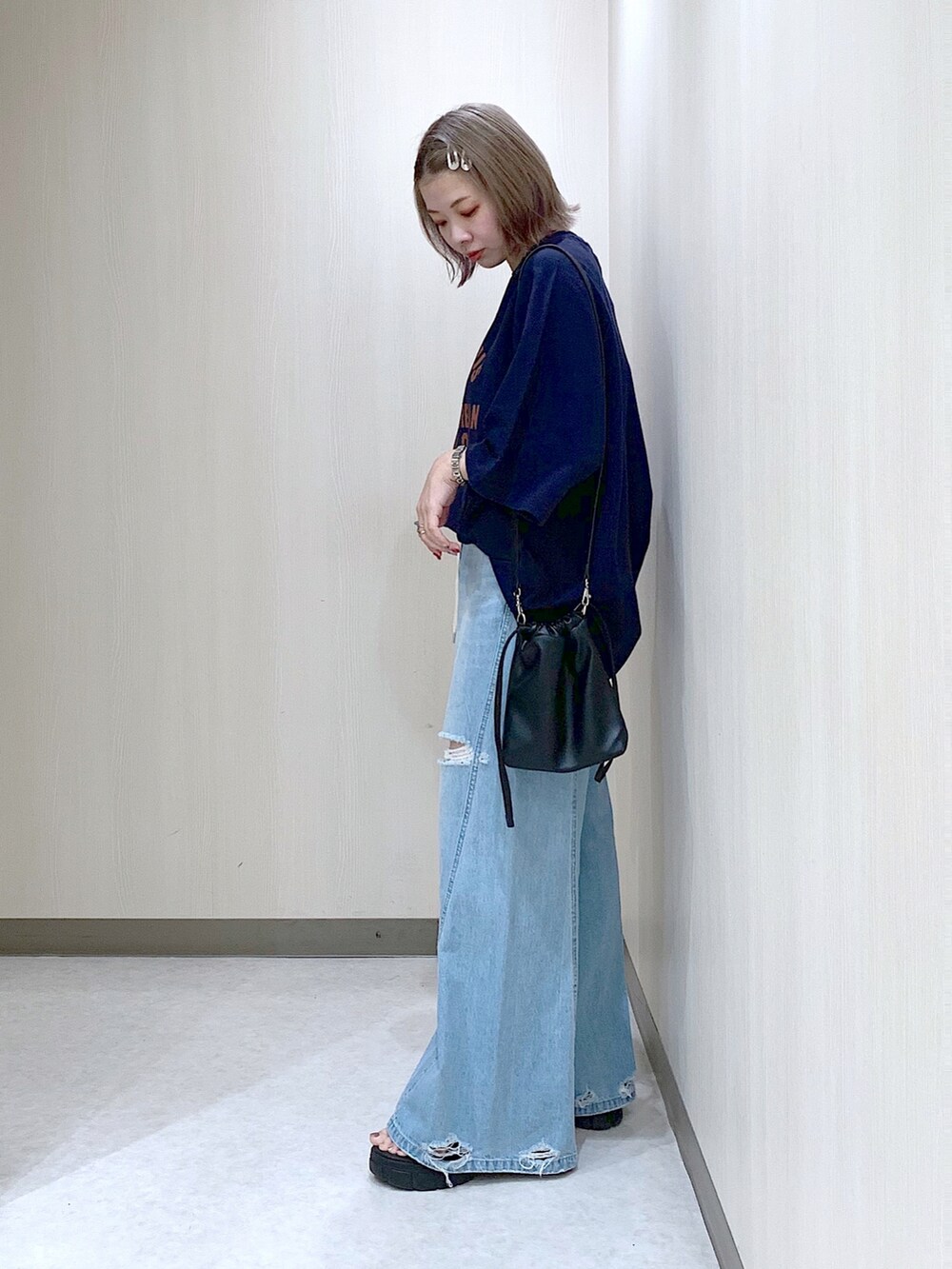 ブルー系のスウェット、ブルー系のデニムパンツ、ブラック系のサンダルを着用したレディースの春コーディネートの4枚目の写真