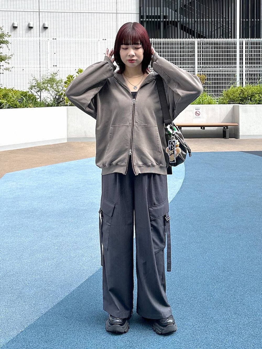 ブラック系のスニーカー、グレー系のスラックス、ブラウン系のパーカーを着用したレディースの秋コーディネートの3枚目の写真