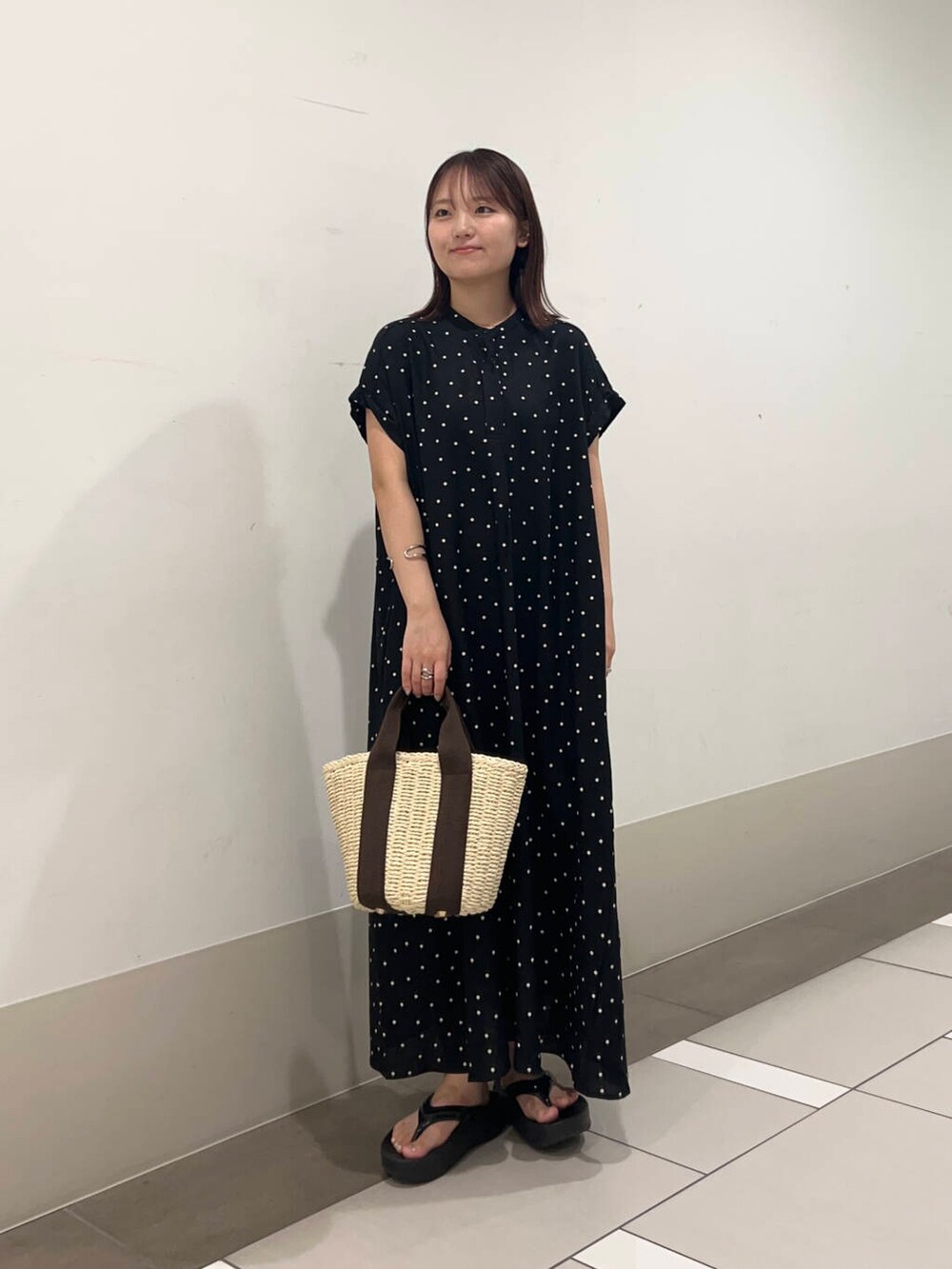 ベージュ系のかごバッグ、ブラック系のワンピースを着用したレディースの夏コーディネートの3枚目の写真