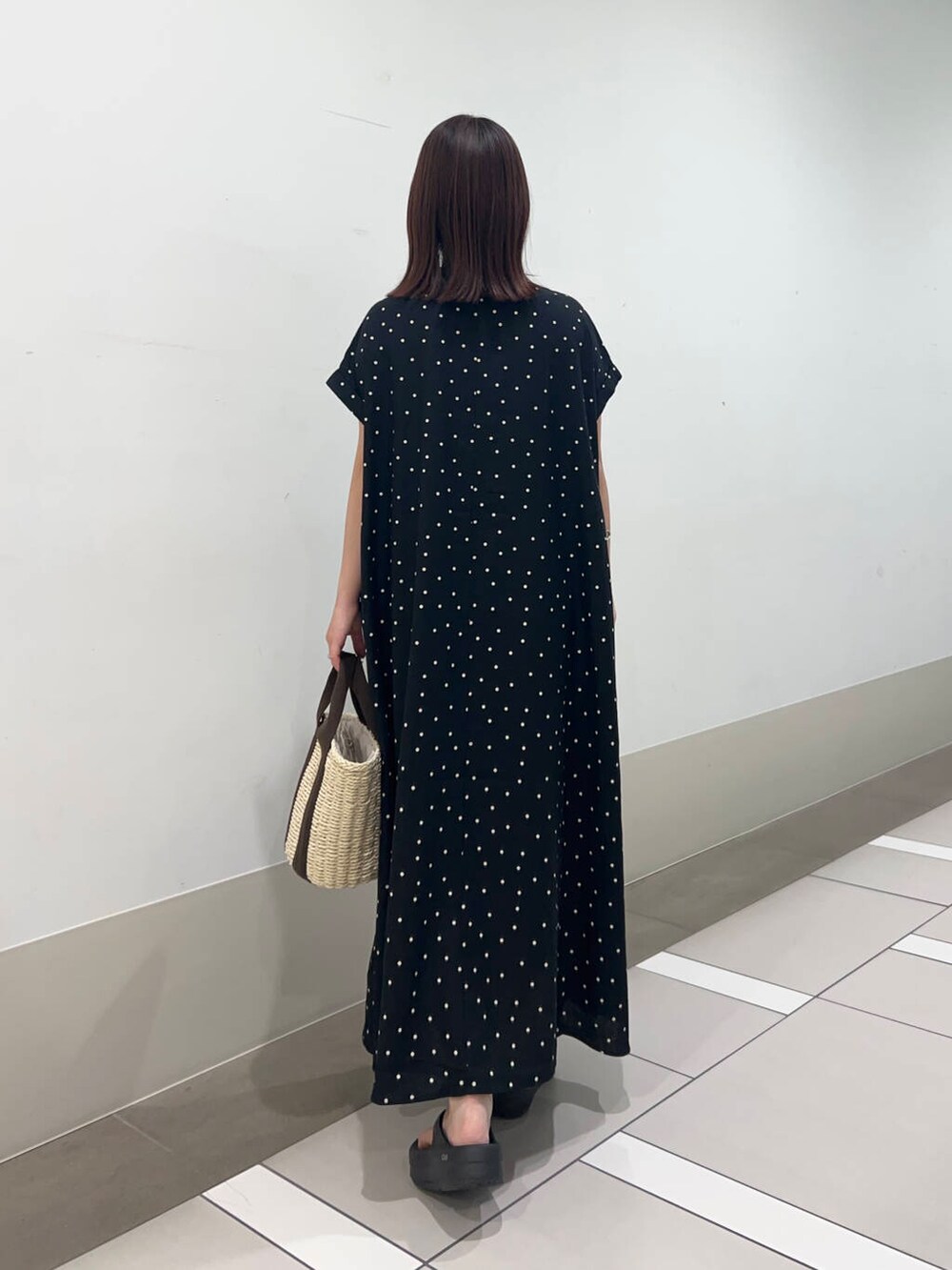 ベージュ系のかごバッグ、ブラック系のワンピースを着用したレディースの夏コーディネートの5枚目の写真