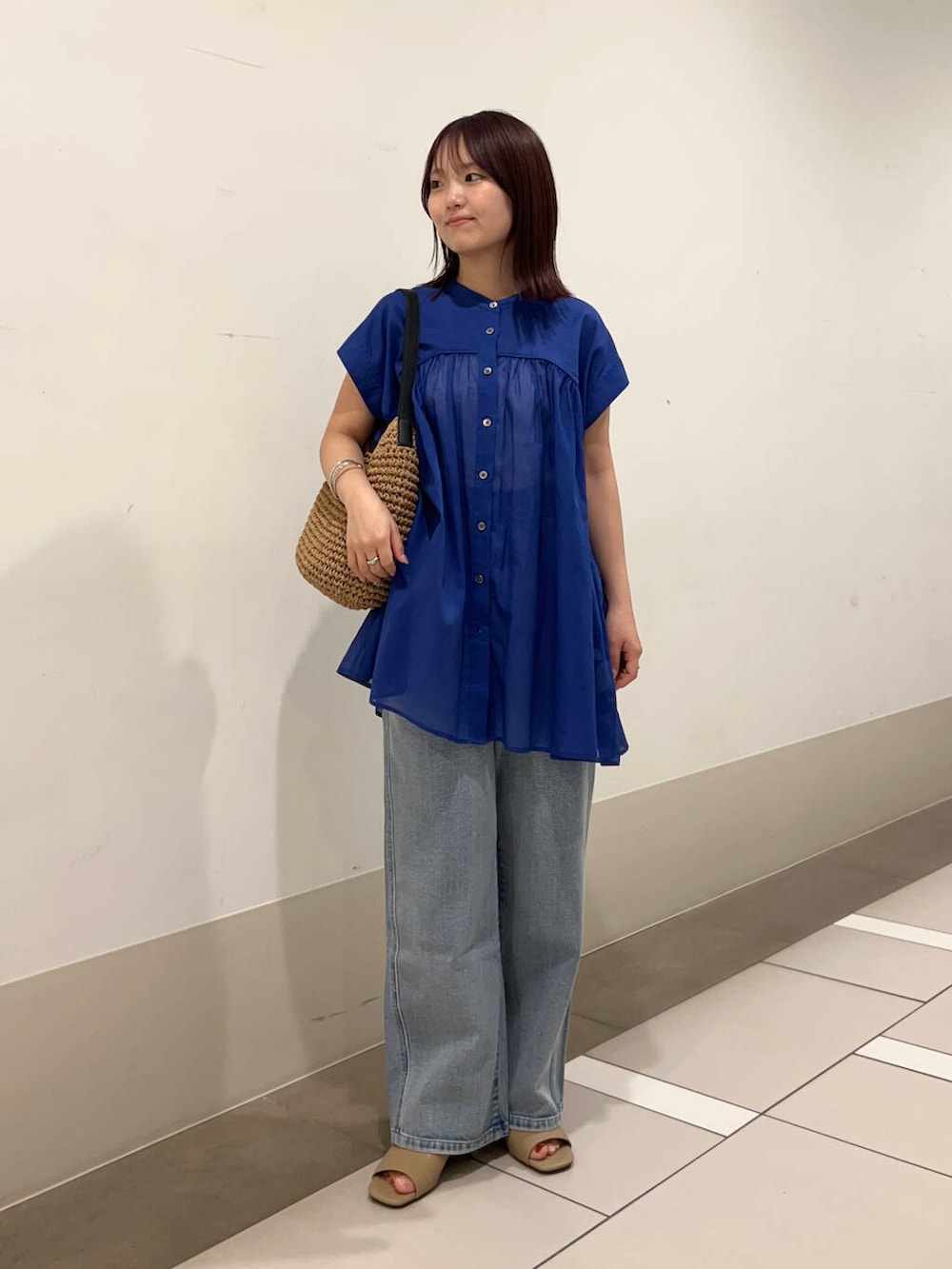 ブルー系のデニムパンツ、イエロー系のトートバッグ、イエロー系のサンダルを着用したレディースの夏コーディネートの2枚目の写真