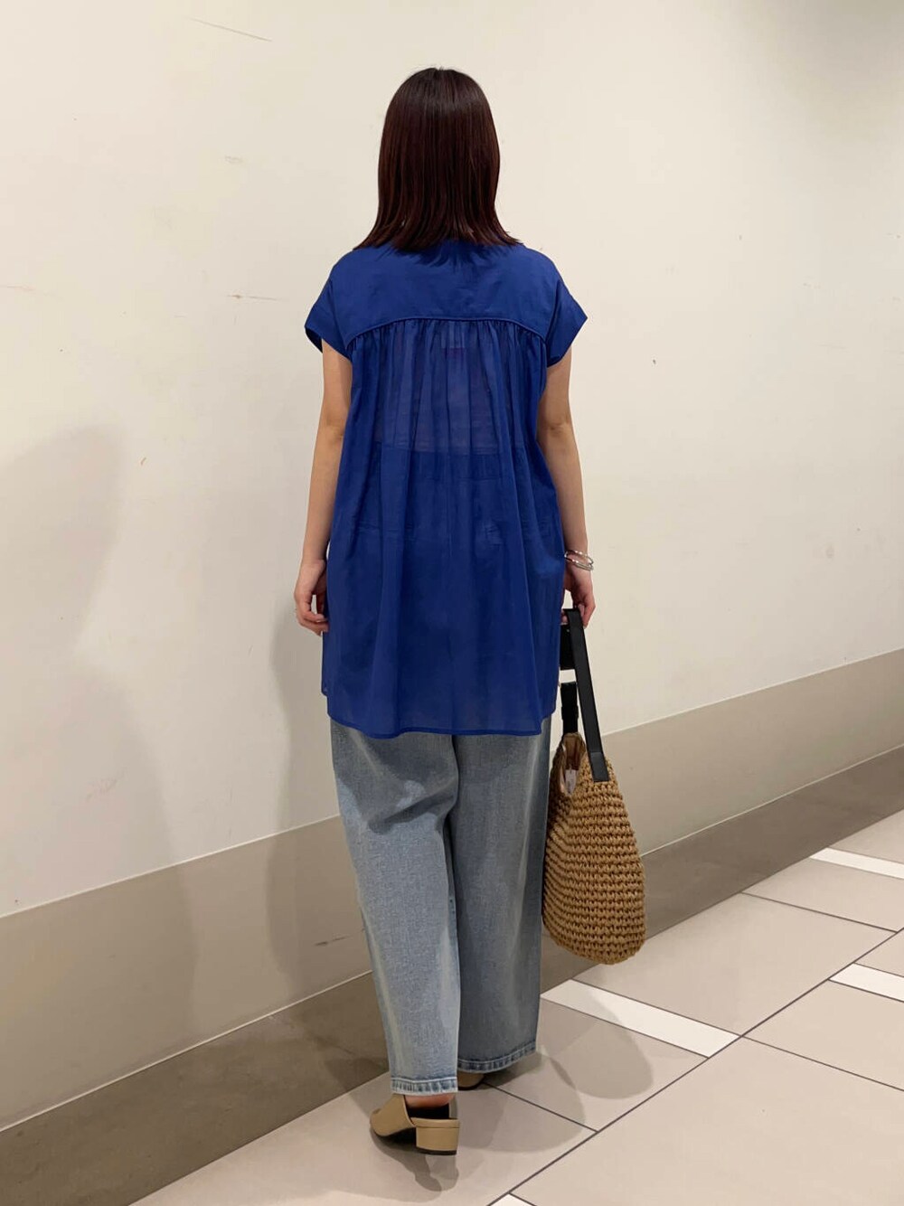 ブルー系のデニムパンツ、イエロー系のトートバッグ、イエロー系のサンダルを着用したレディースの夏コーディネートの4枚目の写真