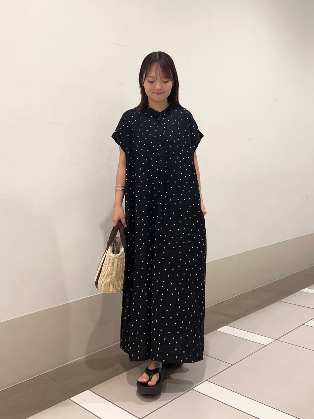 ベージュ系のかごバッグ、ブラック系のワンピースを着用したレディースの夏コーディネートの4枚目の写真