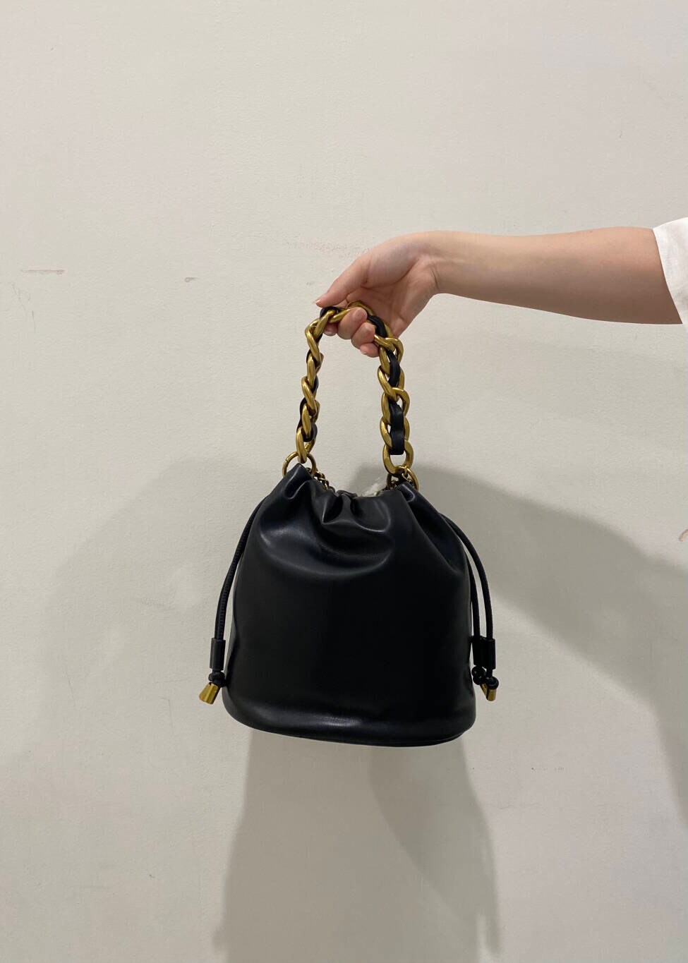 ベージュ系のダウンベスト、ブラック系のショルダーバッグ、ホワイト系のシャツ/ブラウスを着用したレディースの夏コーディネートの6枚目の写真