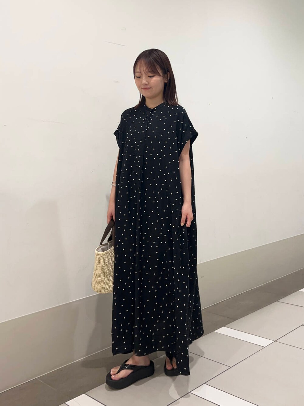 ベージュ系のかごバッグ、ブラック系のワンピースを着用したレディースの夏コーディネートの2枚目の写真