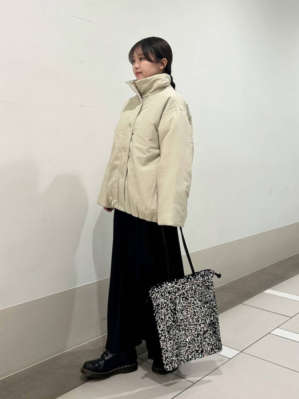 ベージュ系のブルゾン、シルバー系のトートバッグ、ブラック系のスカートを着用したレディースの冬コーディネートの3枚目の写真