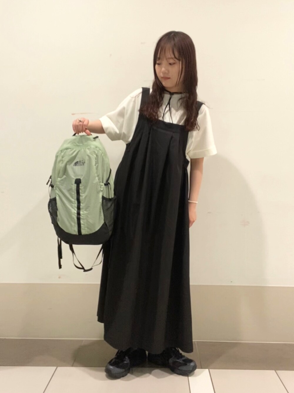 グリーン系のバックパック/リュック、ホワイト系のTシャツ/カットソー、ブラック系のワンピースを着用したレディースの夏コーディネートの2枚目の写真