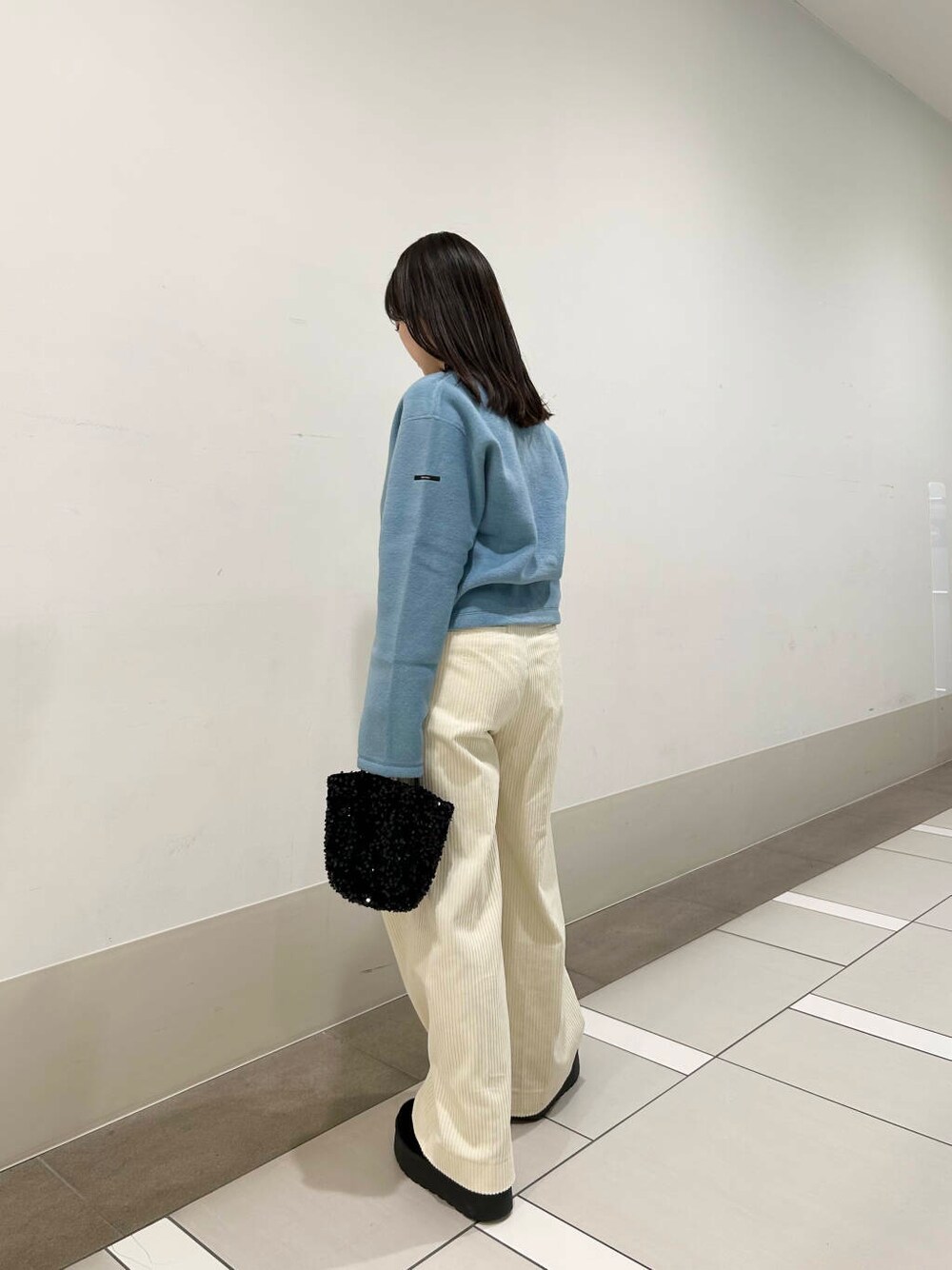 ブラック系のショルダーバッグ、ブルー系のカーディガン/ボレロ、ホワイト系のその他パンツを着用したレディースの冬コーディネートの3枚目の写真