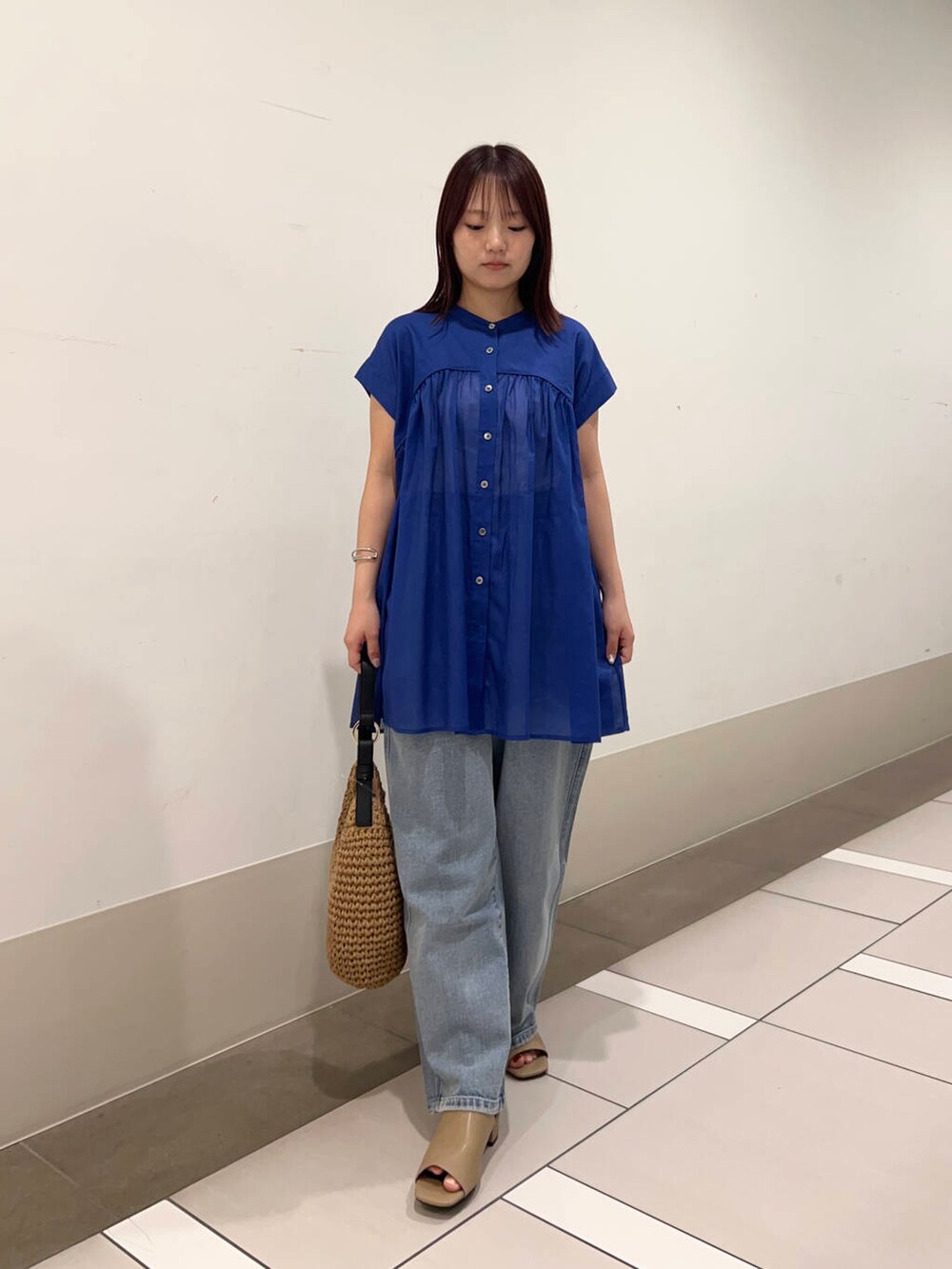 ブルー系のデニムパンツ、イエロー系のトートバッグ、イエロー系のサンダルを着用したレディースの夏コーディネートの3枚目の写真