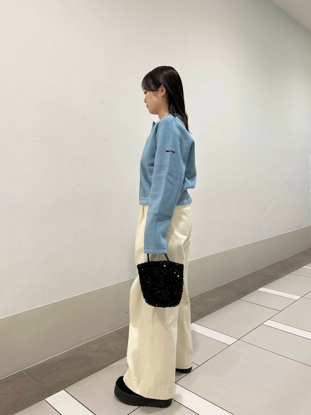 ブラック系のショルダーバッグ、ブルー系のカーディガン/ボレロ、ホワイト系のその他パンツを着用したレディースの冬コーディネートの2枚目の写真