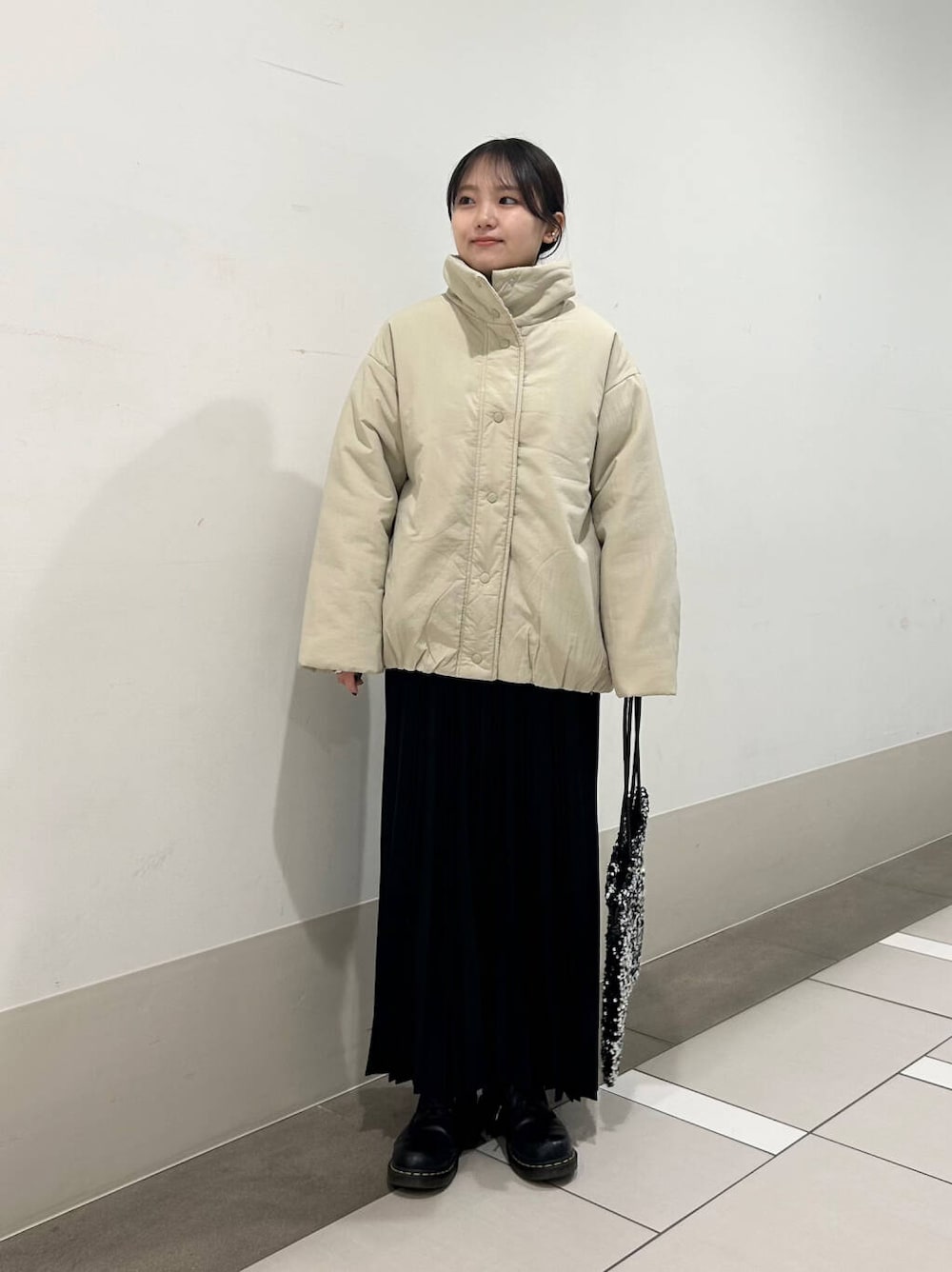 ベージュ系のブルゾン、シルバー系のトートバッグ、ブラック系のスカートを着用したレディースの冬コーディネートの2枚目の写真