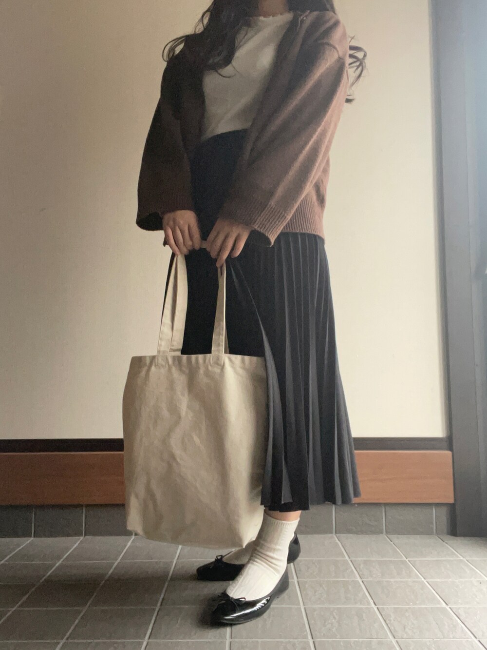 ブラウン系のカーディガン/ボレロ、ホワイト系のTシャツ/カットソー、ブラック系のスカートを着用したレディースの秋コーディネートの2枚目の写真