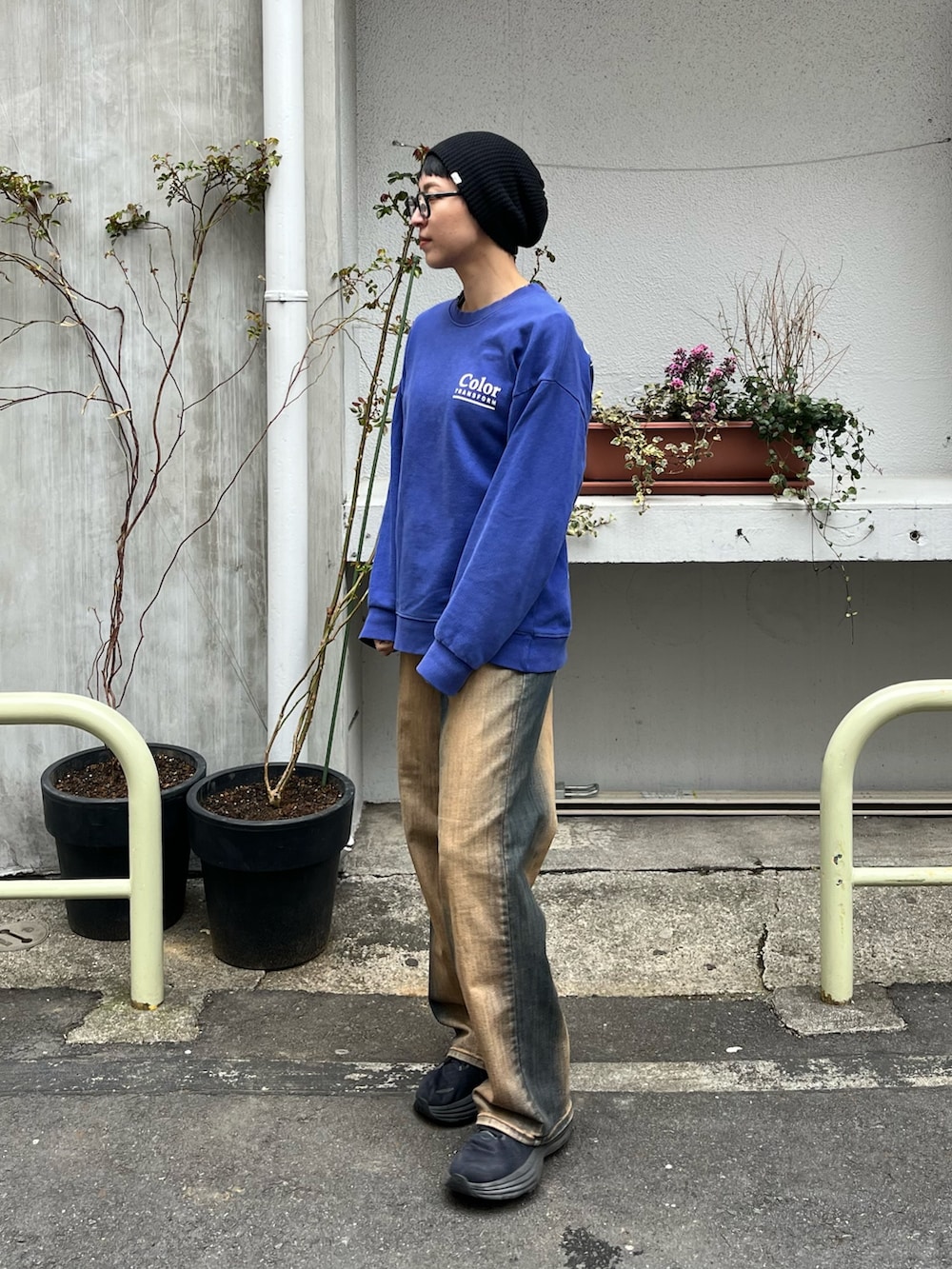 ブルー系のトップス、ブラウン系のデニムパンツ、ブラック系のスニーカーを着用したレディースの春コーディネートの2枚目の写真