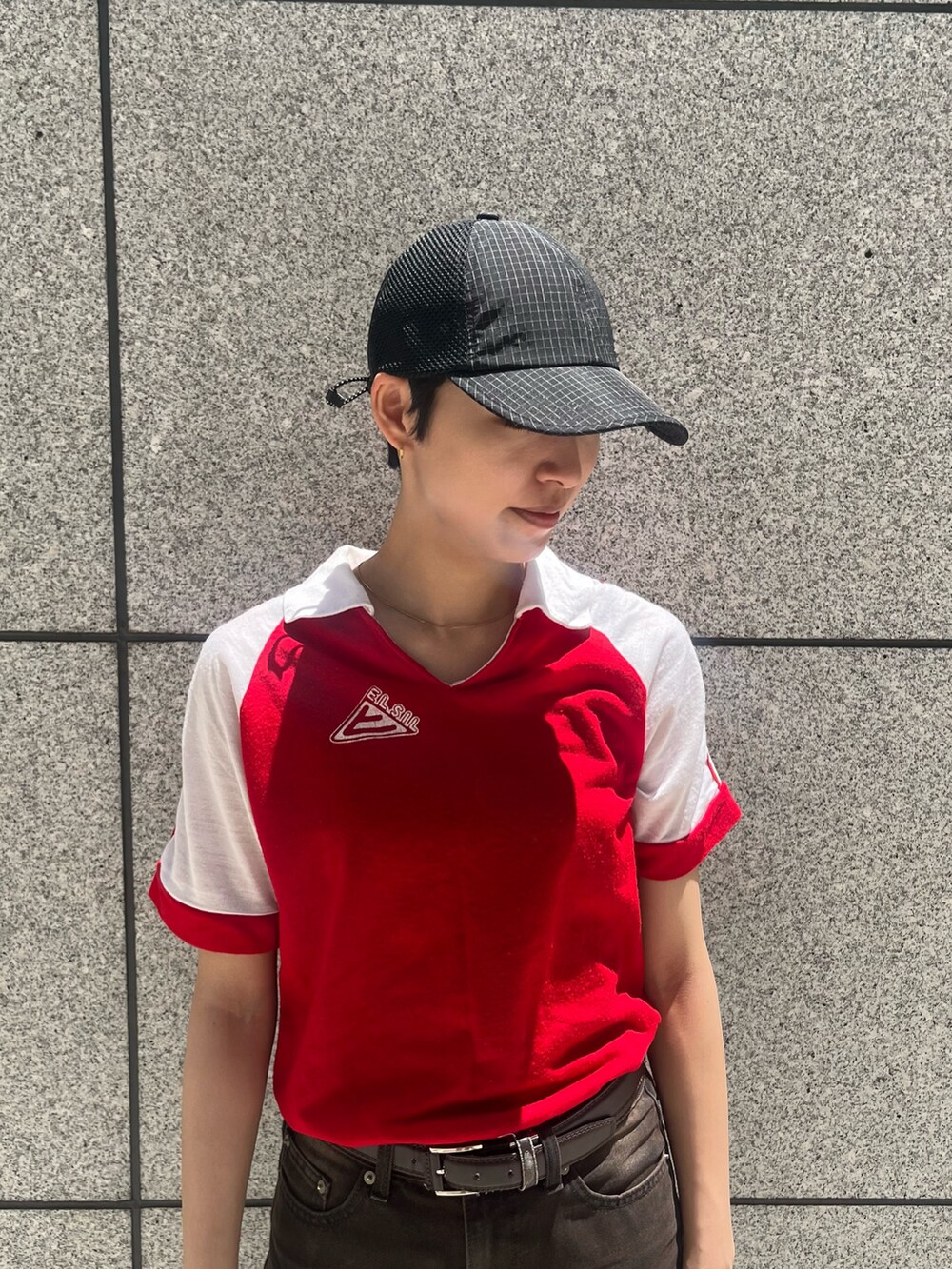 レッド系のトップス、ブラウン系のデニムパンツ、ブラック系のスニーカーを着用したレディースの夏コーディネートの2枚目の写真