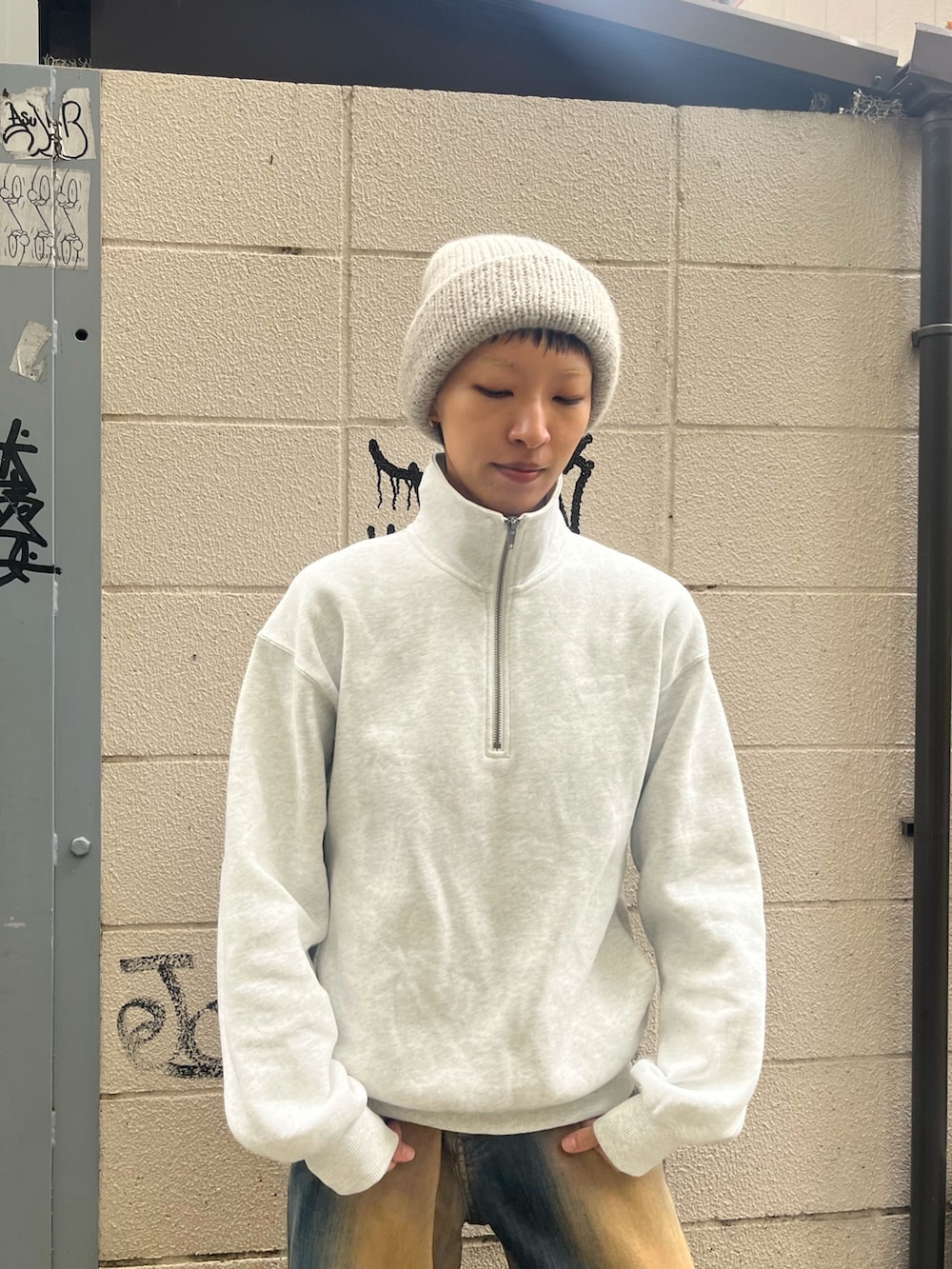 ブラウン系のデニムパンツ、ブラック系のスニーカー、グレー系のニットキャップ/ビーニーを着用したレディースの秋コーディネートの3枚目の写真