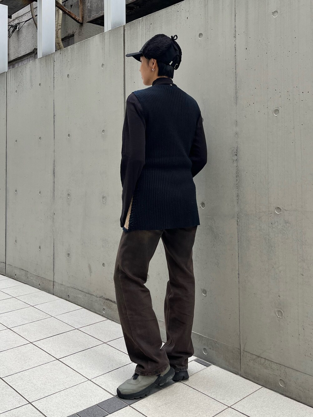 ベージュ系のベスト、ブラウン系のデニムパンツ、ブラック系のキャップを着用したレディースの冬コーディネートの2枚目の写真