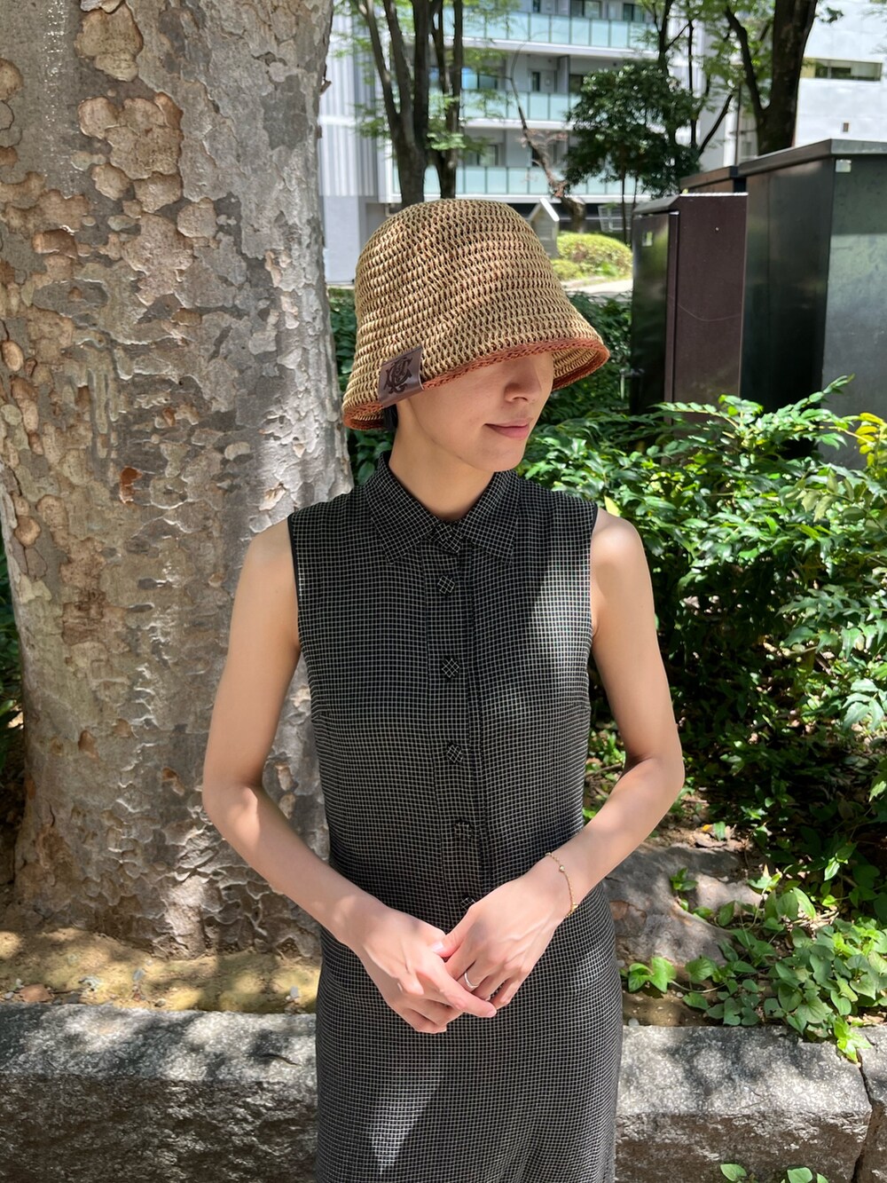 ブラック系のワンピース、ブラック系のサンダル、ベージュ系のハットを着用したレディースの夏コーディネートの2枚目の写真