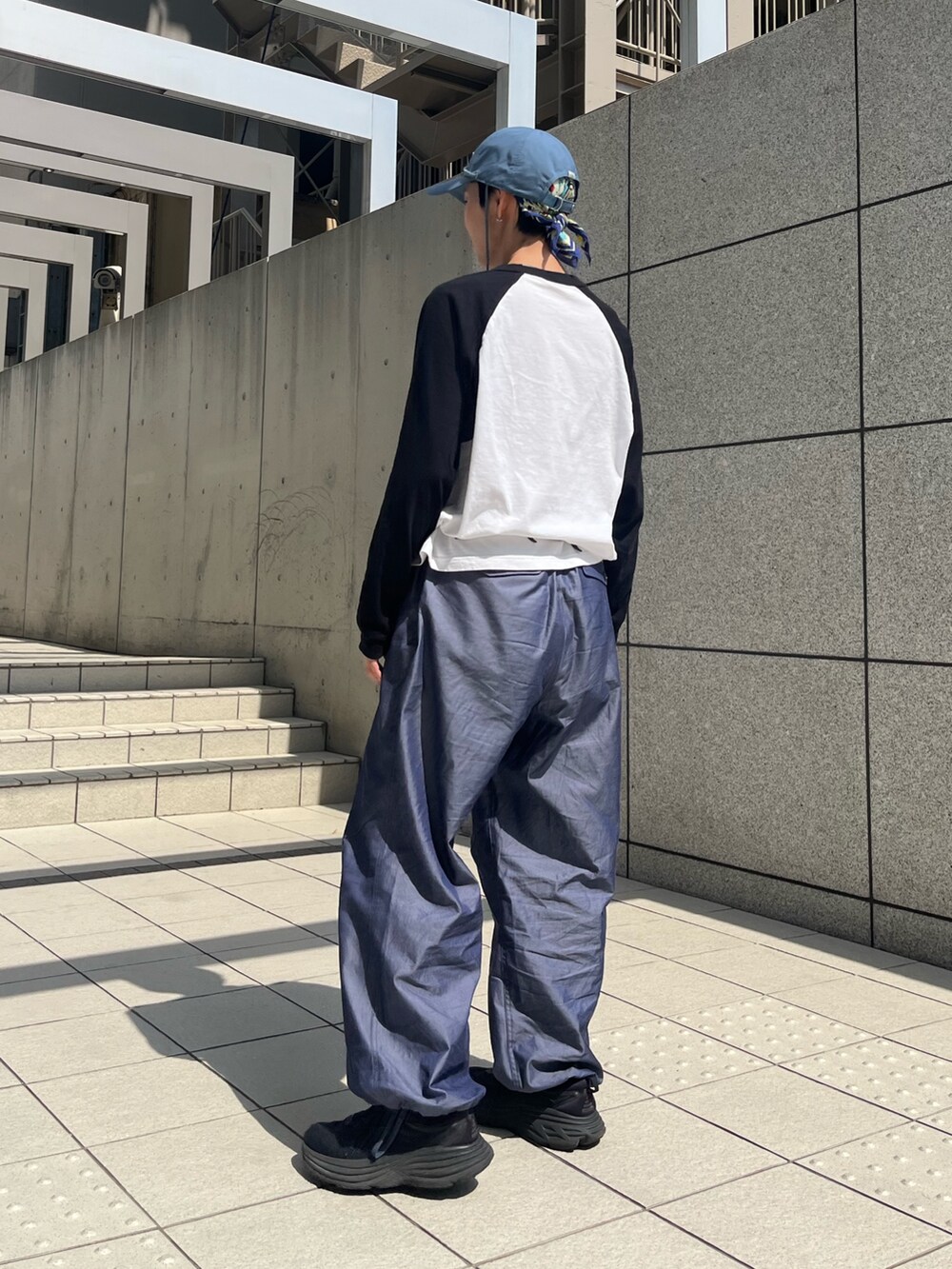 ブルー系のカーゴパンツ、ブラック系のスニーカー、ブルー系のキャップを着用したレディースの春コーディネートの2枚目の写真