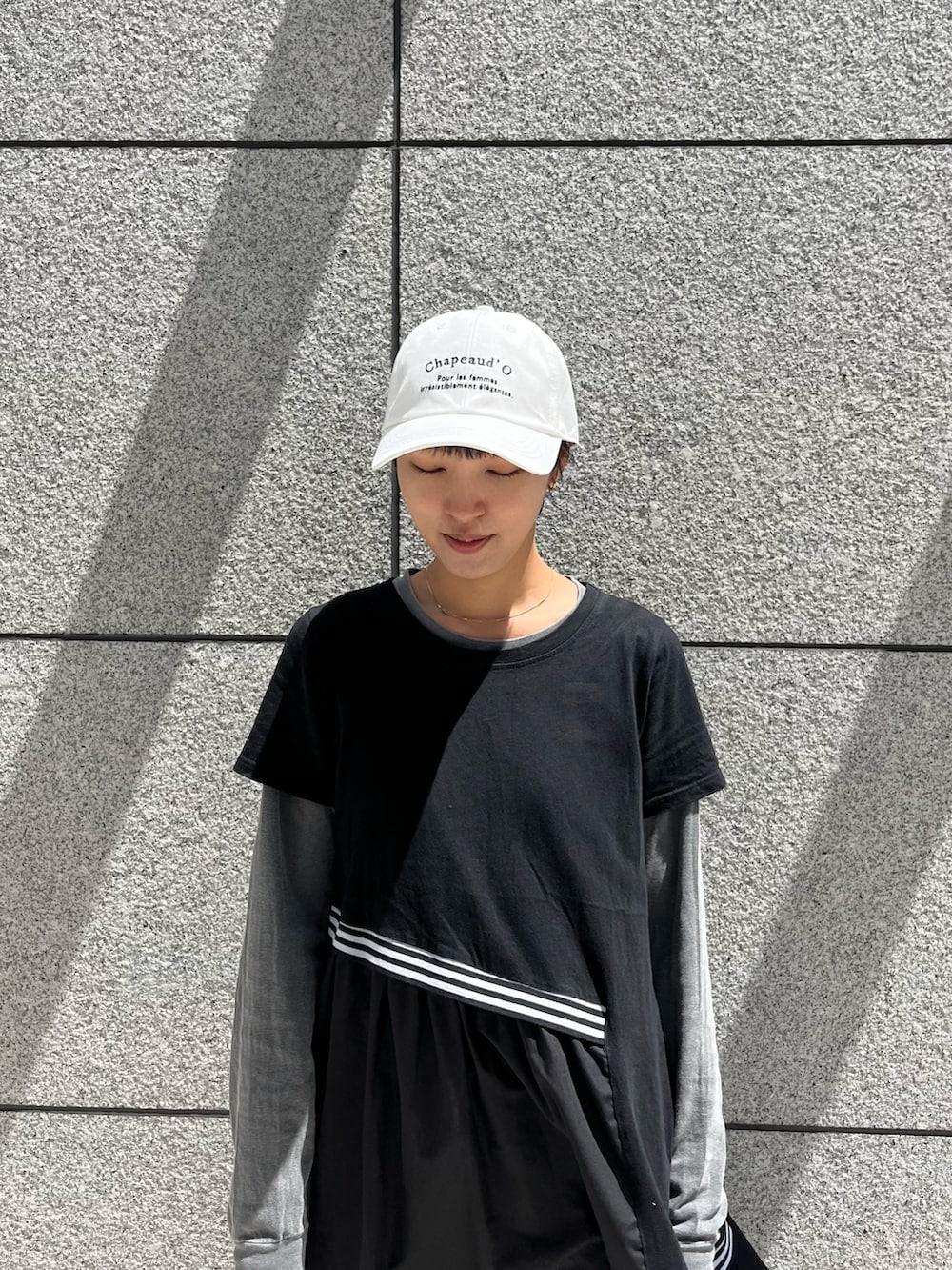 ブラック系のワンピース、ブラウン系のデニムパンツ、ブラック系のスニーカーを着用したレディースの春コーディネートの2枚目の写真