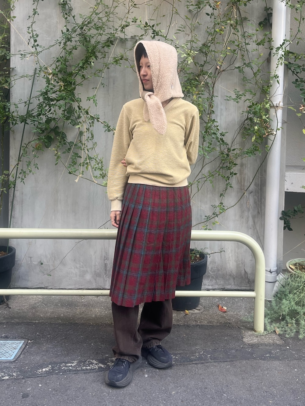 イエロー系のトップス、レッド系のスカート、ブラウン系のデニムパンツを着用したレディースの冬コーディネートの2枚目の写真