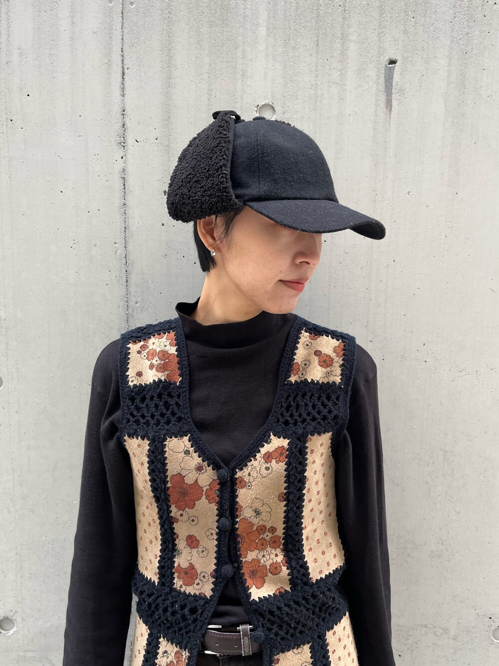 ベージュ系のベスト、ブラウン系のデニムパンツ、ブラック系のキャップを着用したレディースの冬コーディネートの3枚目の写真