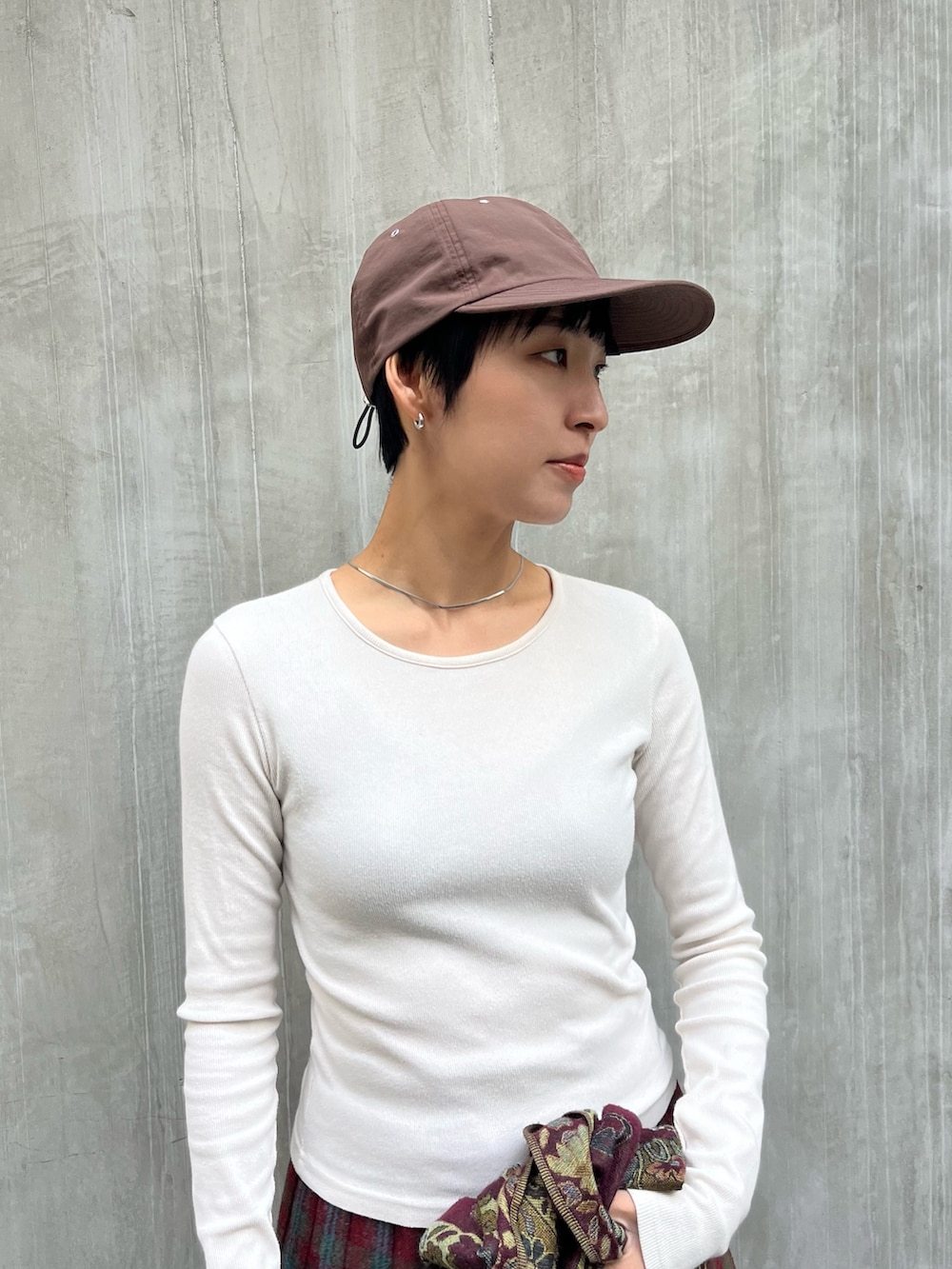 レッド系のスカート、ブラウン系のデニムパンツ、ブラウン系のキャップを着用したレディースの冬コーディネートの2枚目の写真