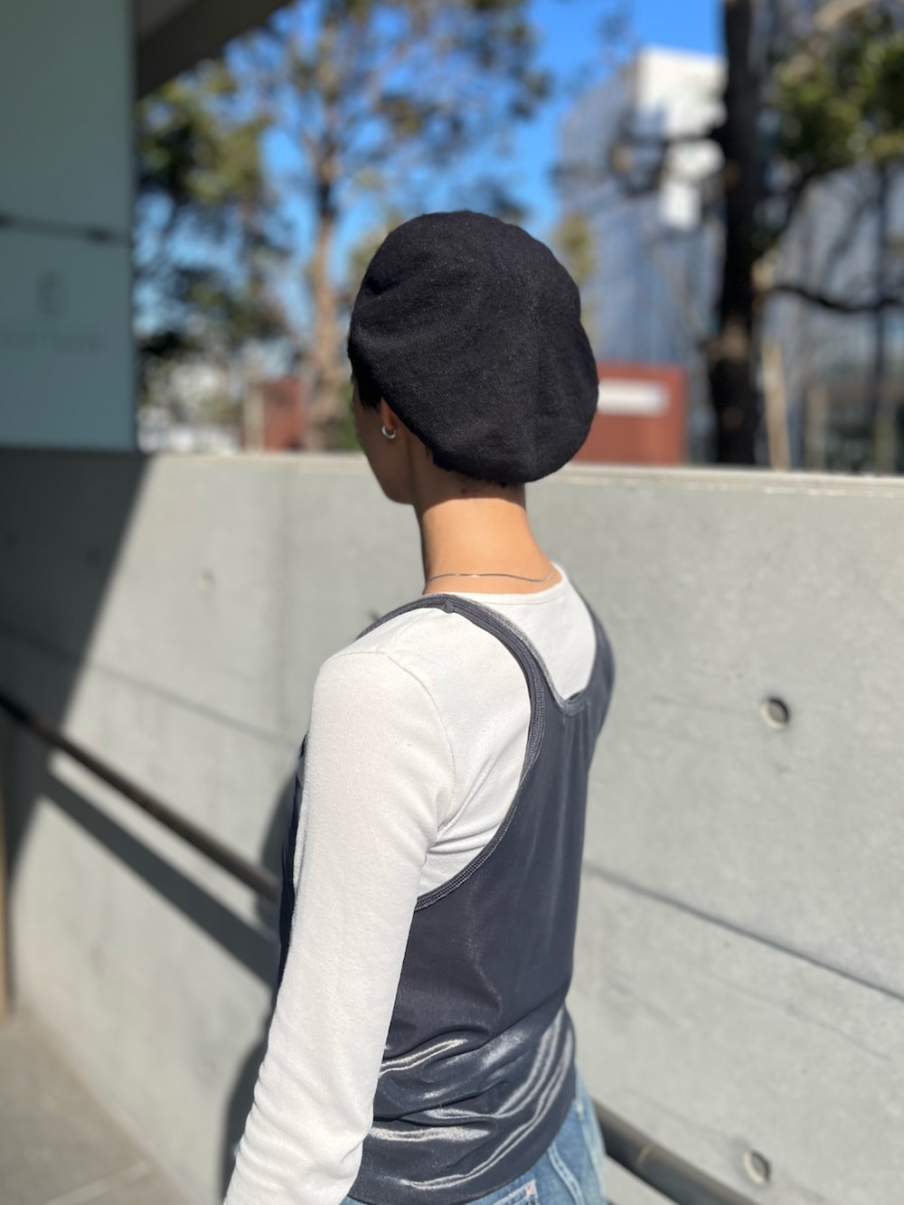 グレー系のタンクトップ、ブルー系のデニムパンツ、ブラック系のスニーカーを着用したレディースの冬コーディネートの2枚目の写真