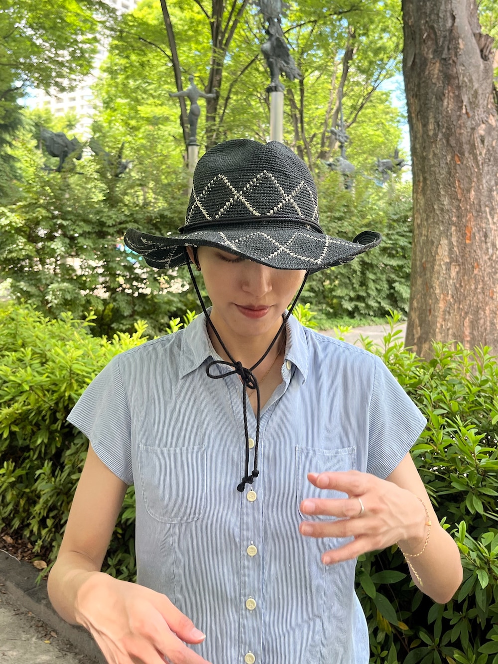 ブルー系のシャツ/ブラウス、ブラック系のスニーカー、ブラック系のハットを着用したレディースの夏コーディネートの2枚目の写真