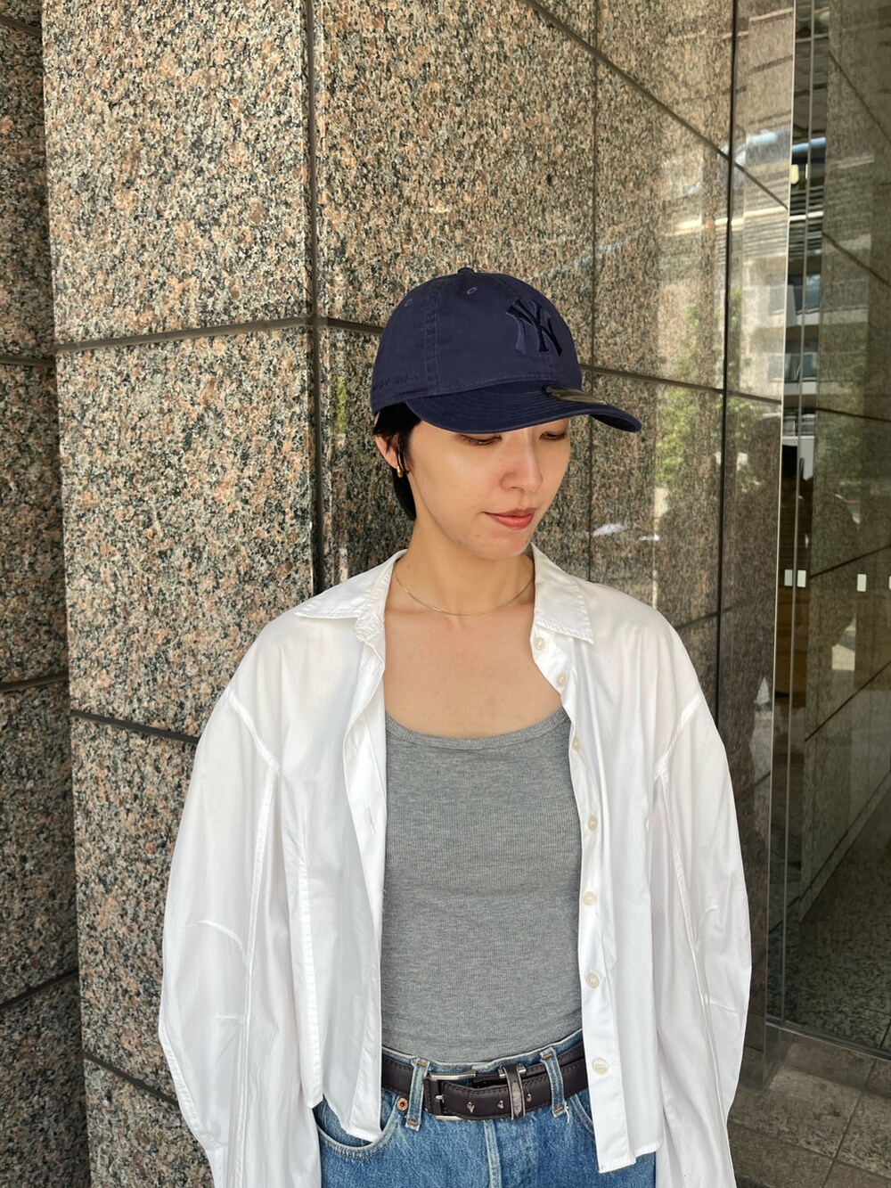 ホワイト系のシャツ/ブラウス、ブラック系のスニーカー、ブルー系のキャップを着用したレディースの夏コーディネートの2枚目の写真