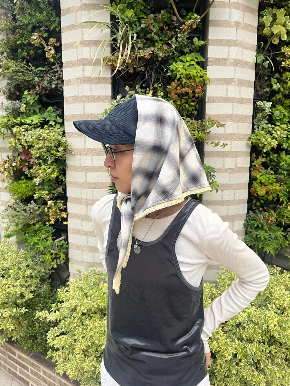 グレー系のタンクトップ、ブラック系のスニーカー、ブルー系のキャップを着用したレディースの秋コーディネートの2枚目の写真